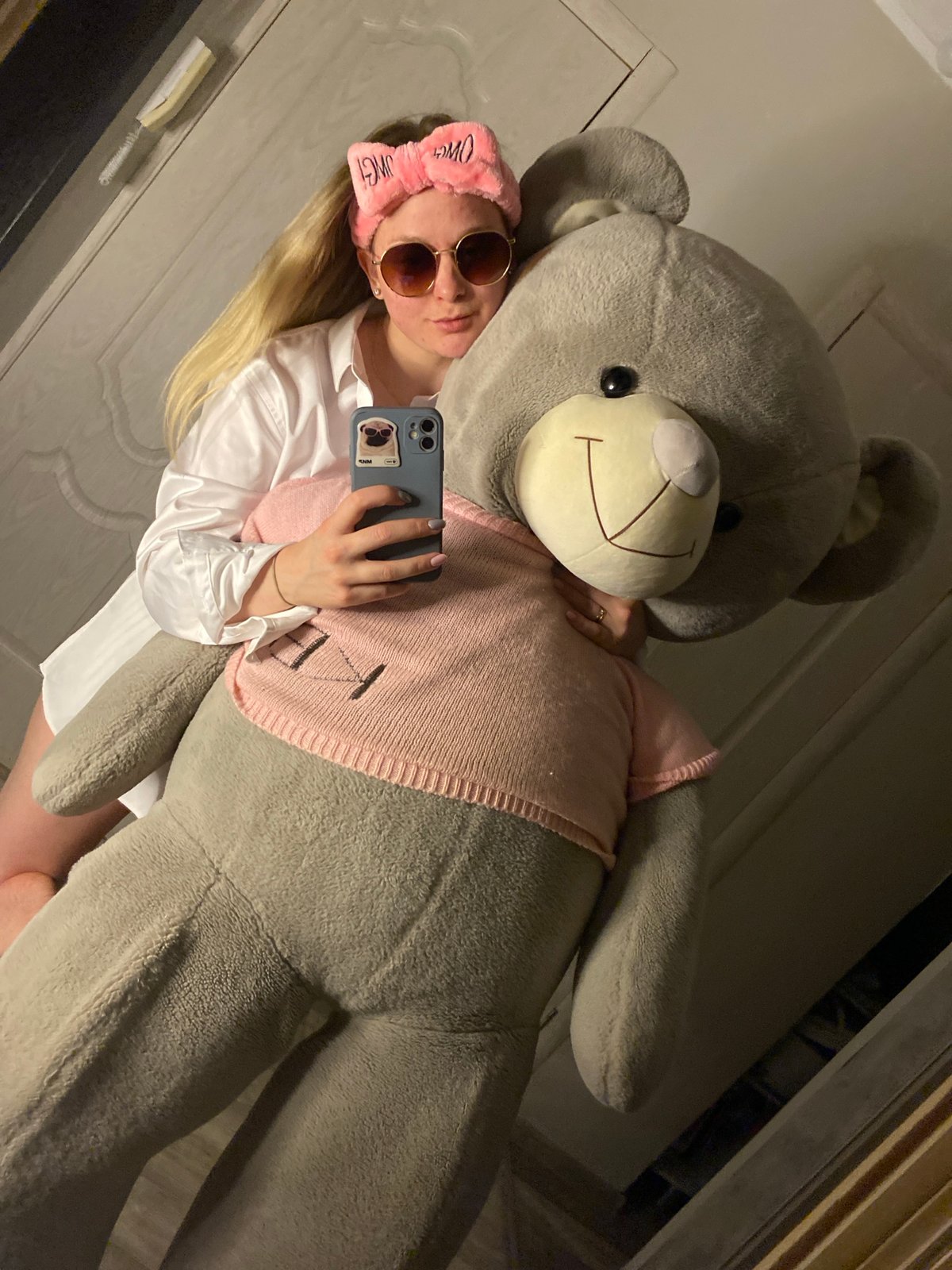 Young woman photographed with teddy bear, pink headband indoors