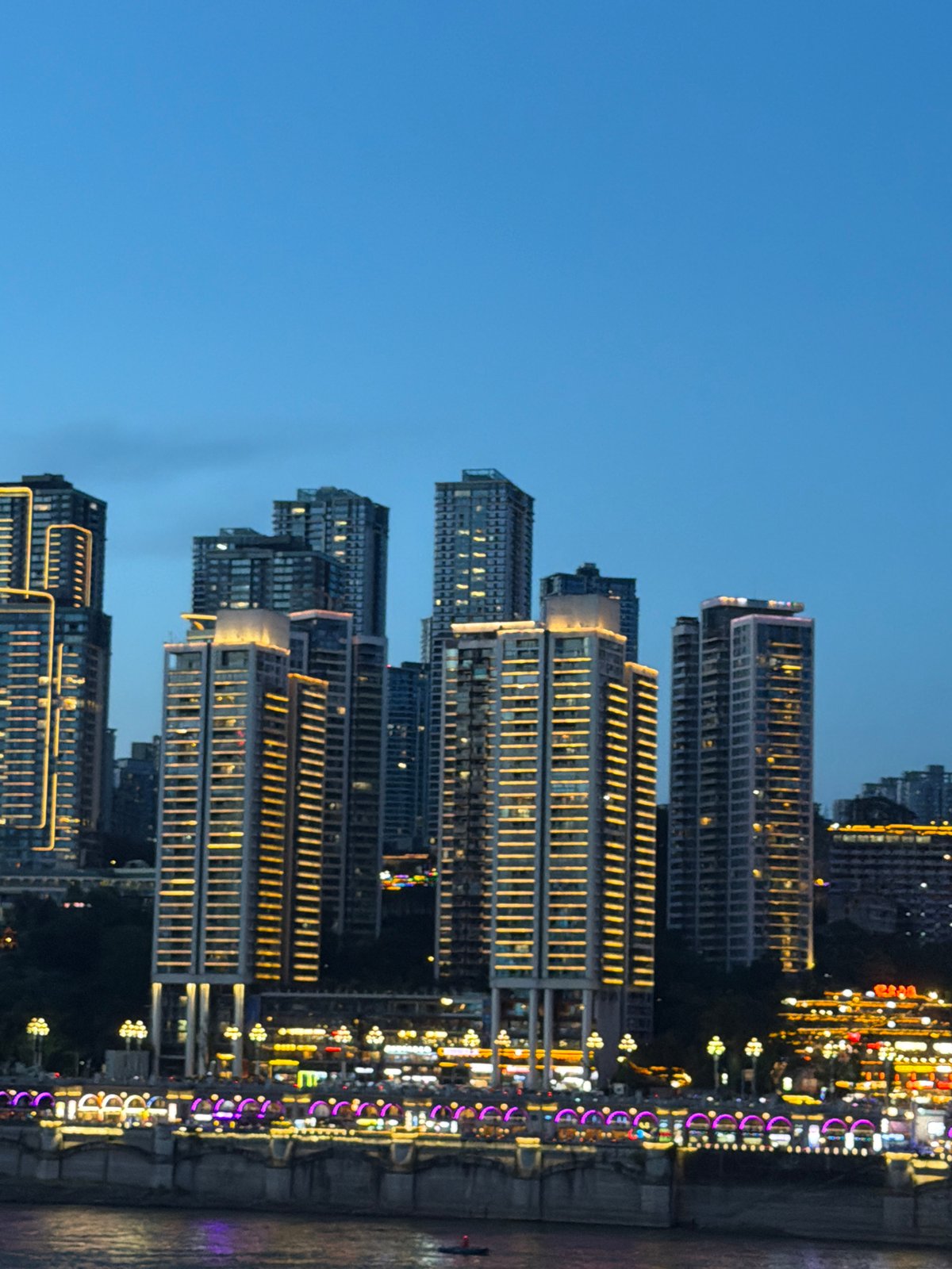 Chongqing's Raffles City towers glow red over a busy riverfront