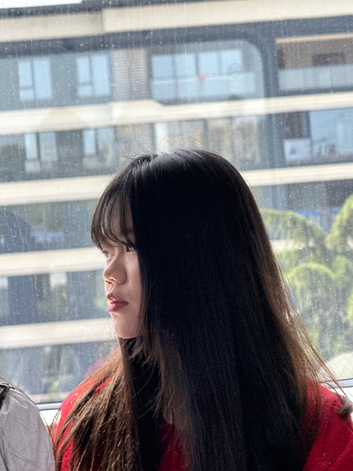 Person gazes at cityscape through window in Shuangfu