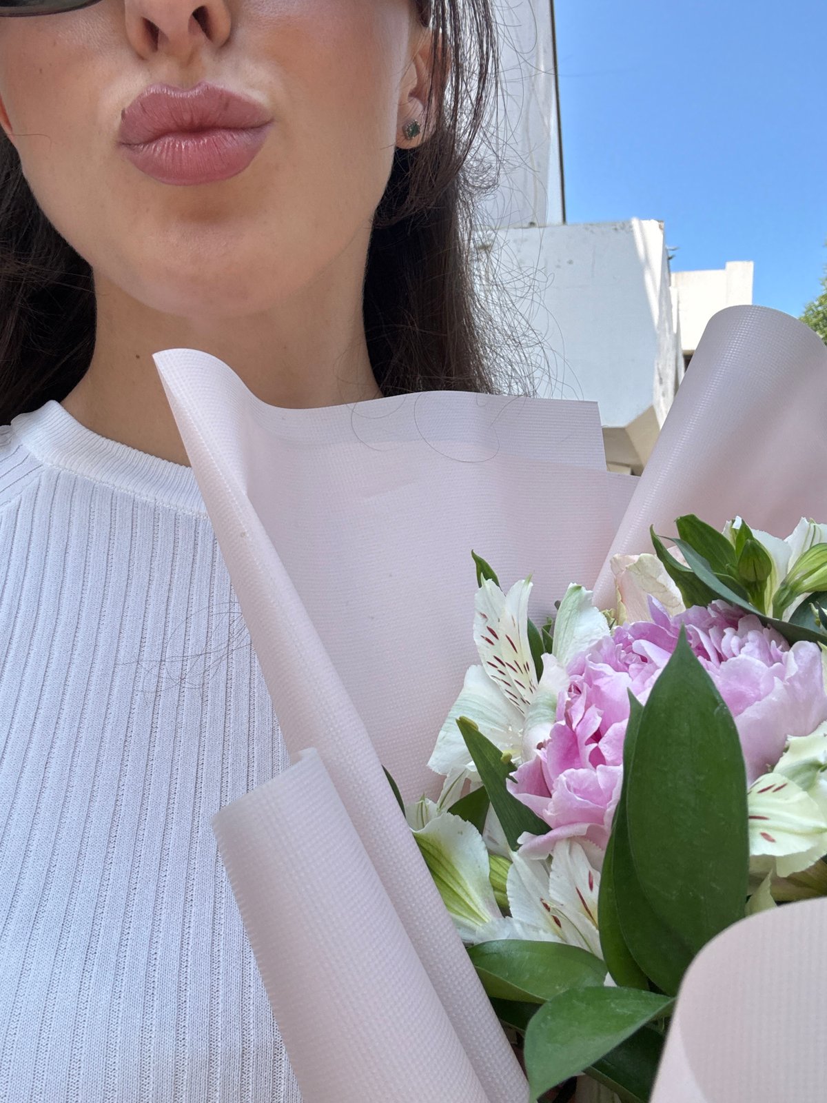 Woman carries flower bouquet through sunny Holon streets