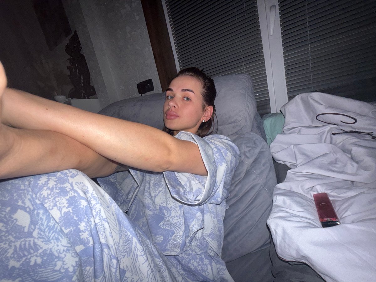 Woman rests on bed while watching television in Лобаново