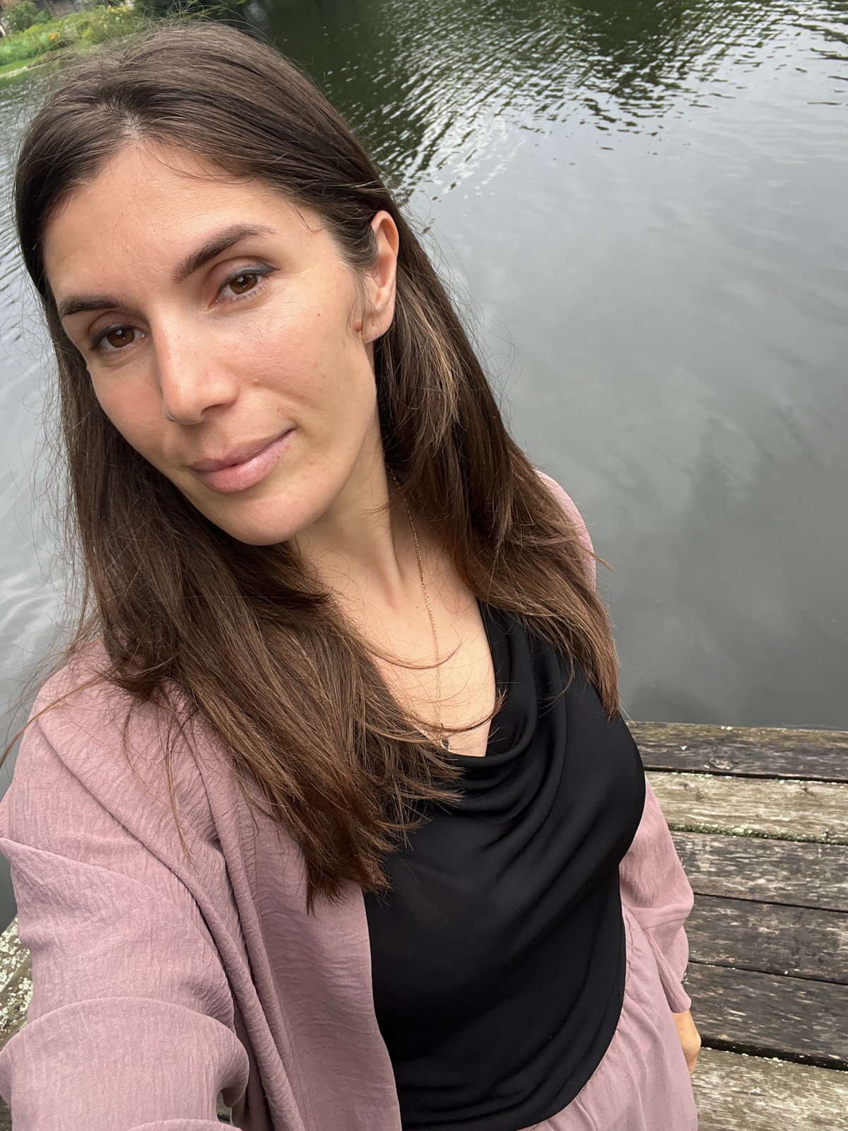 Quiet lakeside dock with lily pads under cloudy skies