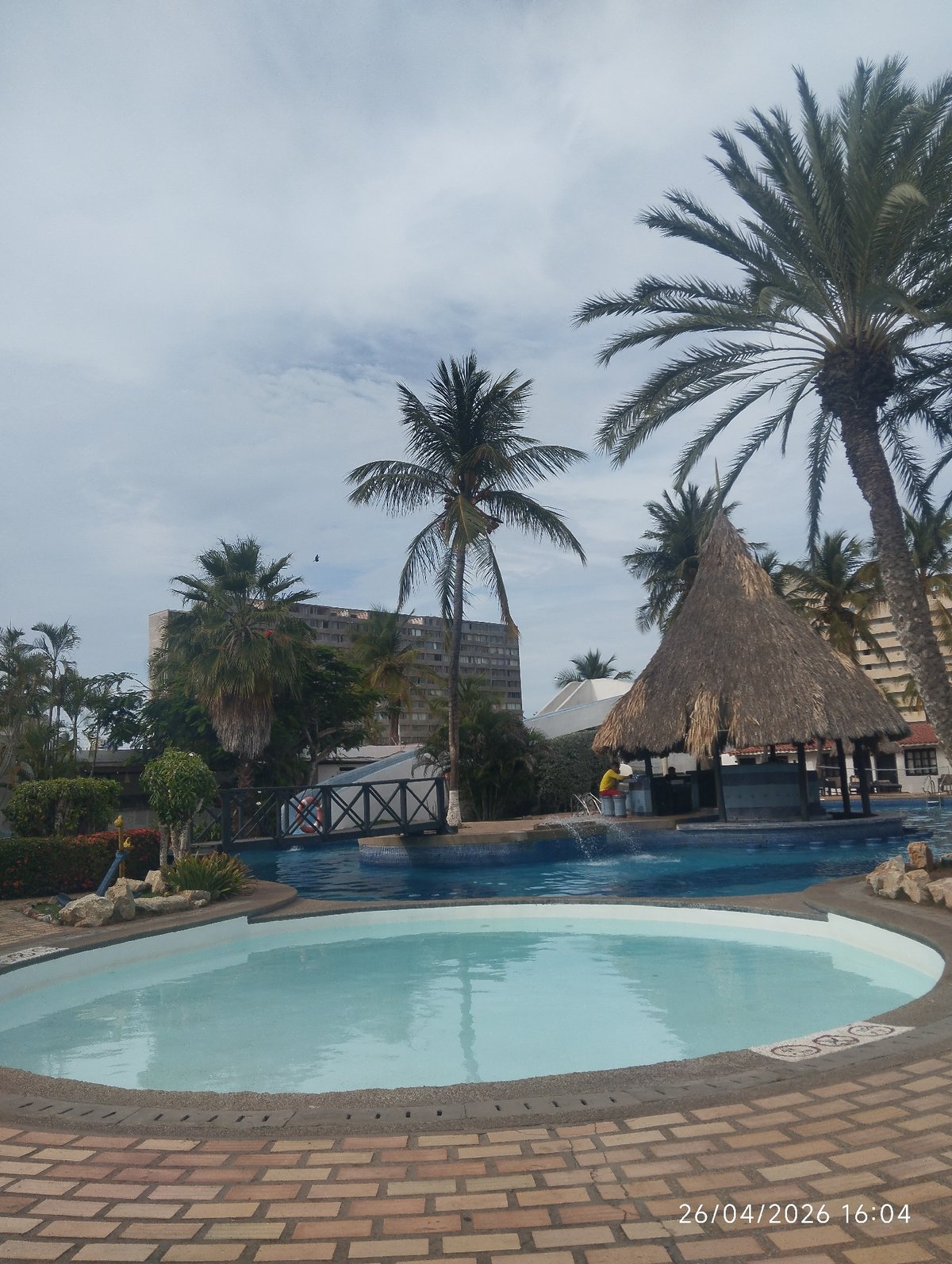 Person enjoys evening at tropical resort pool complex