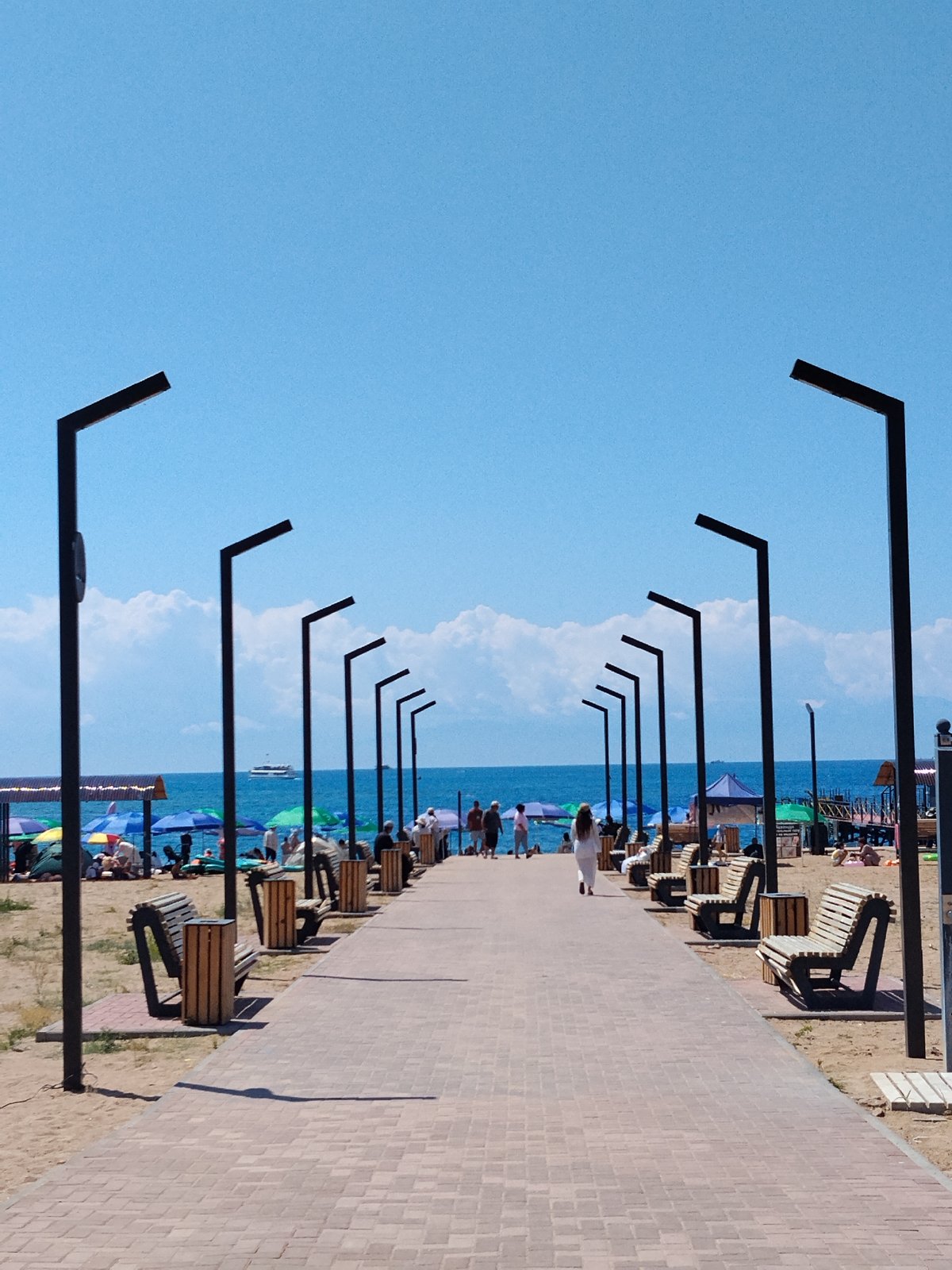 Crowded beach day with waterfront walkway and nearby food stalls