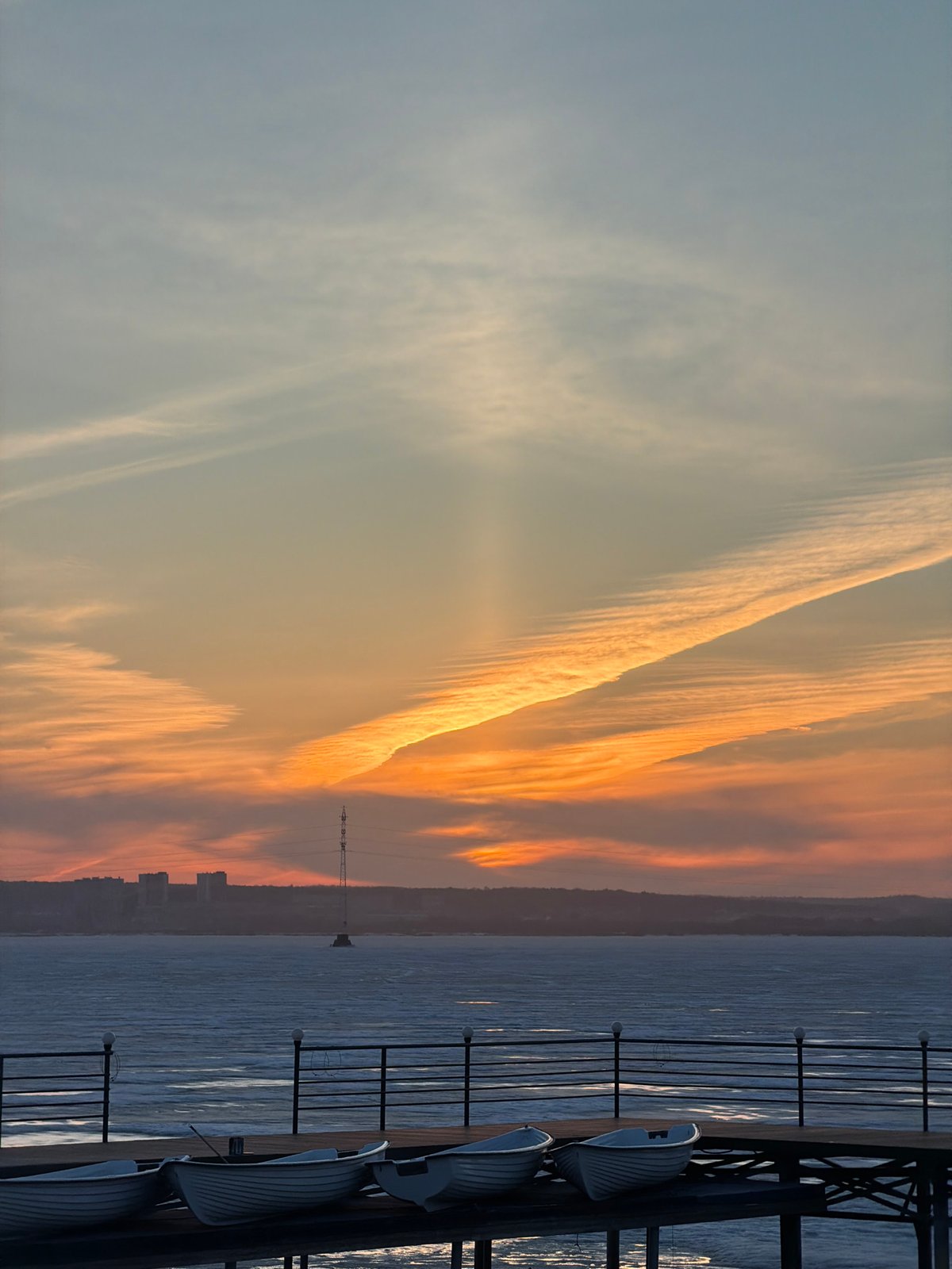 Sunset observed over Izhevsk Pond with birds and city silhouettes