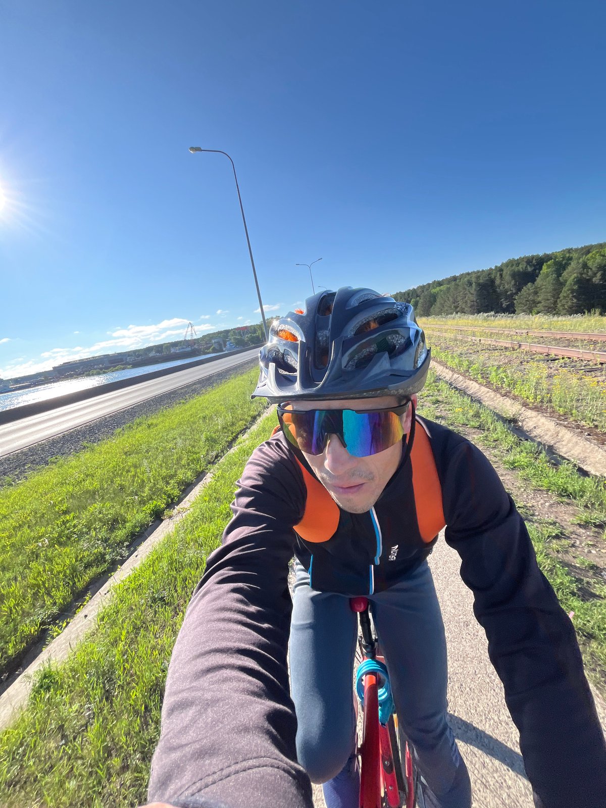 Cyclist rides red bike near water in Chaikovsky, Russia
