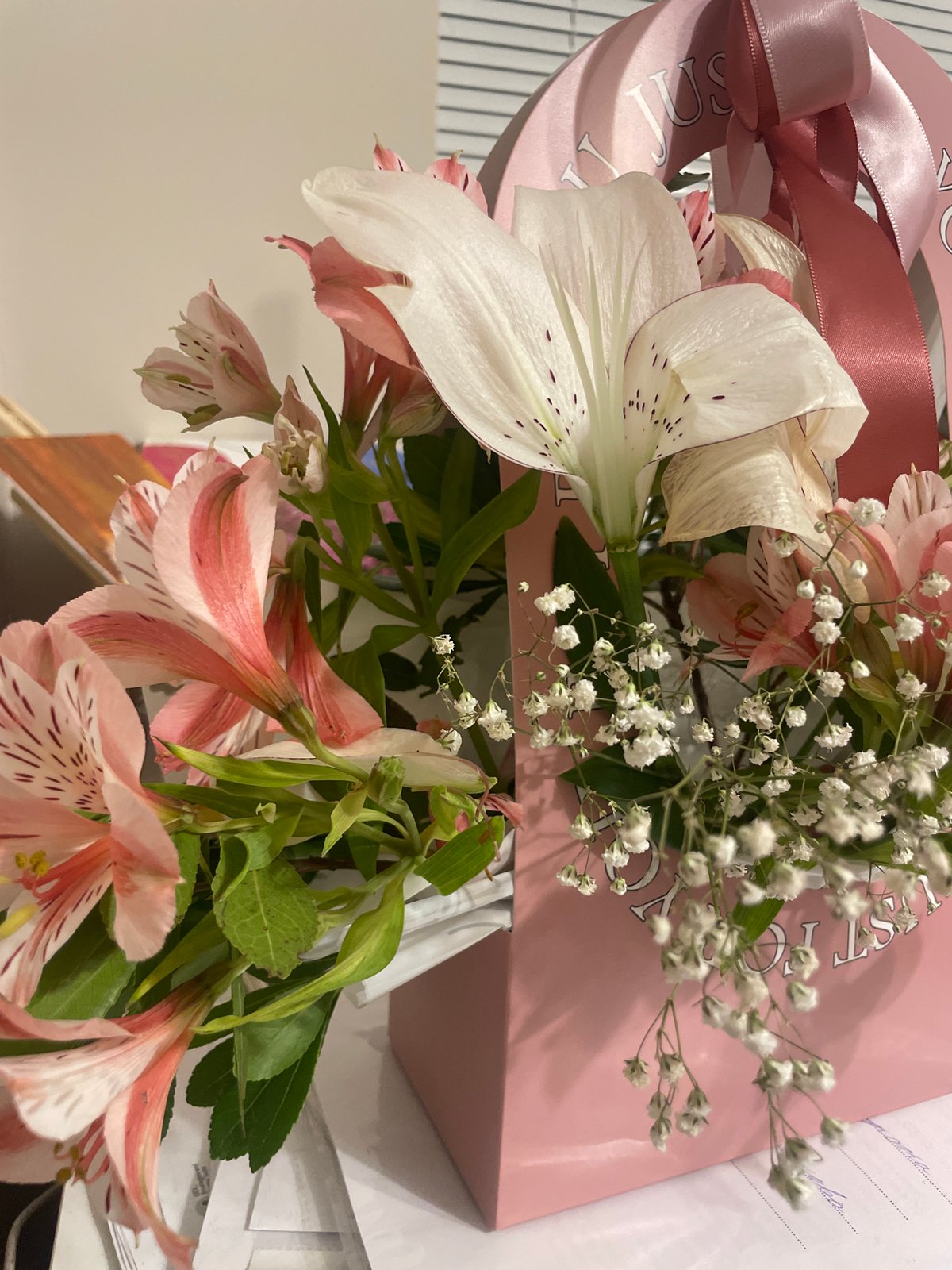 Flowers, a gift bag, and a relaxed tabby cat at home