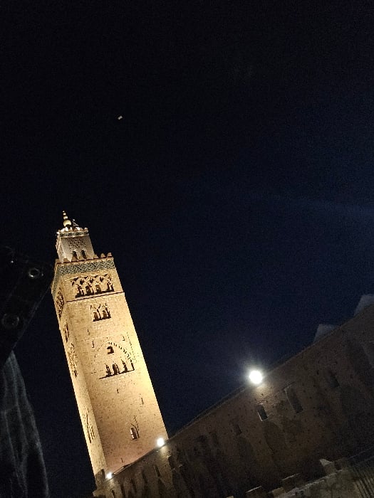 Tourist documents evening visit to illuminated Marrakesh minaret
