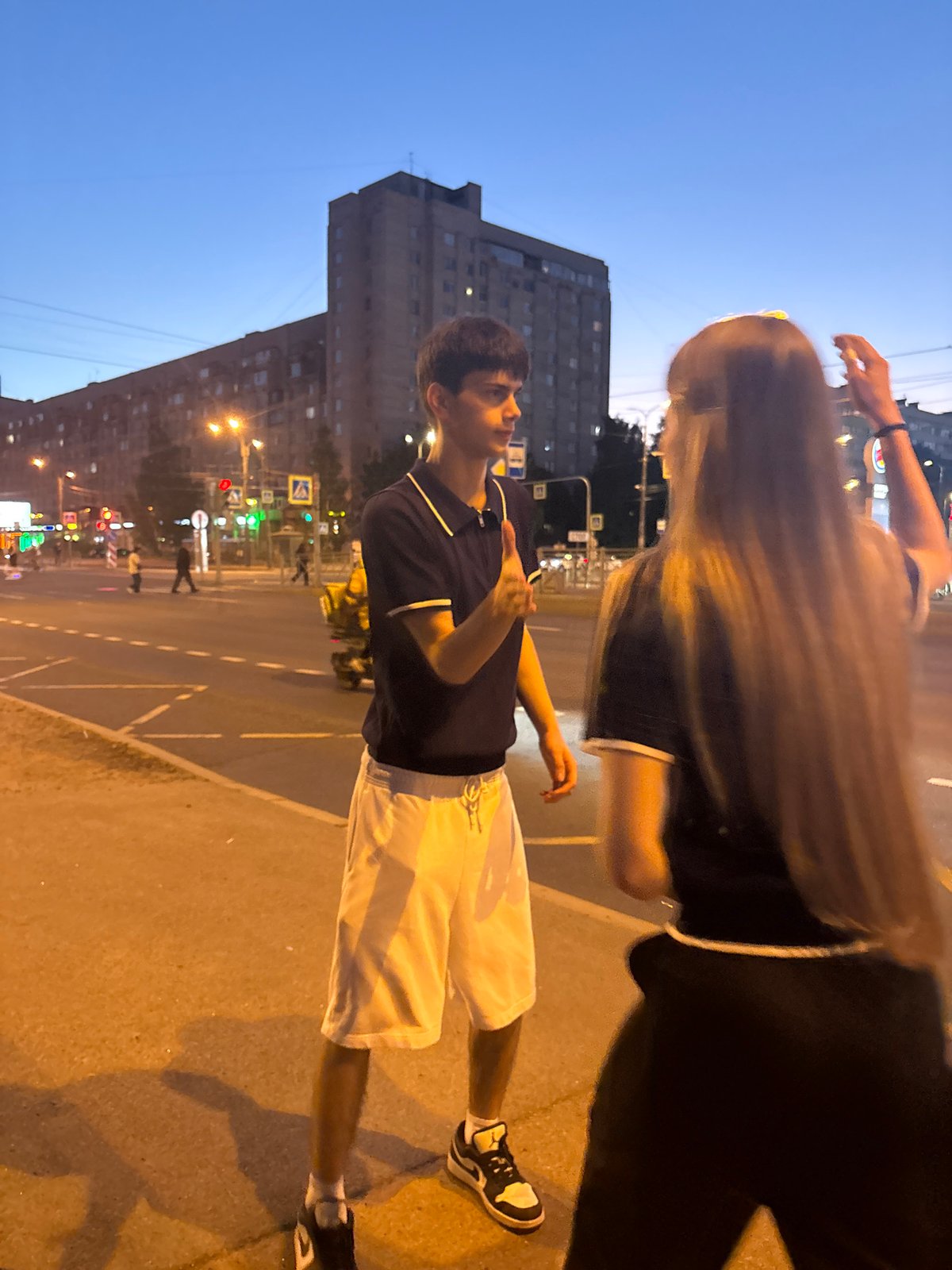 Two youths converse on Russian street during evening hours