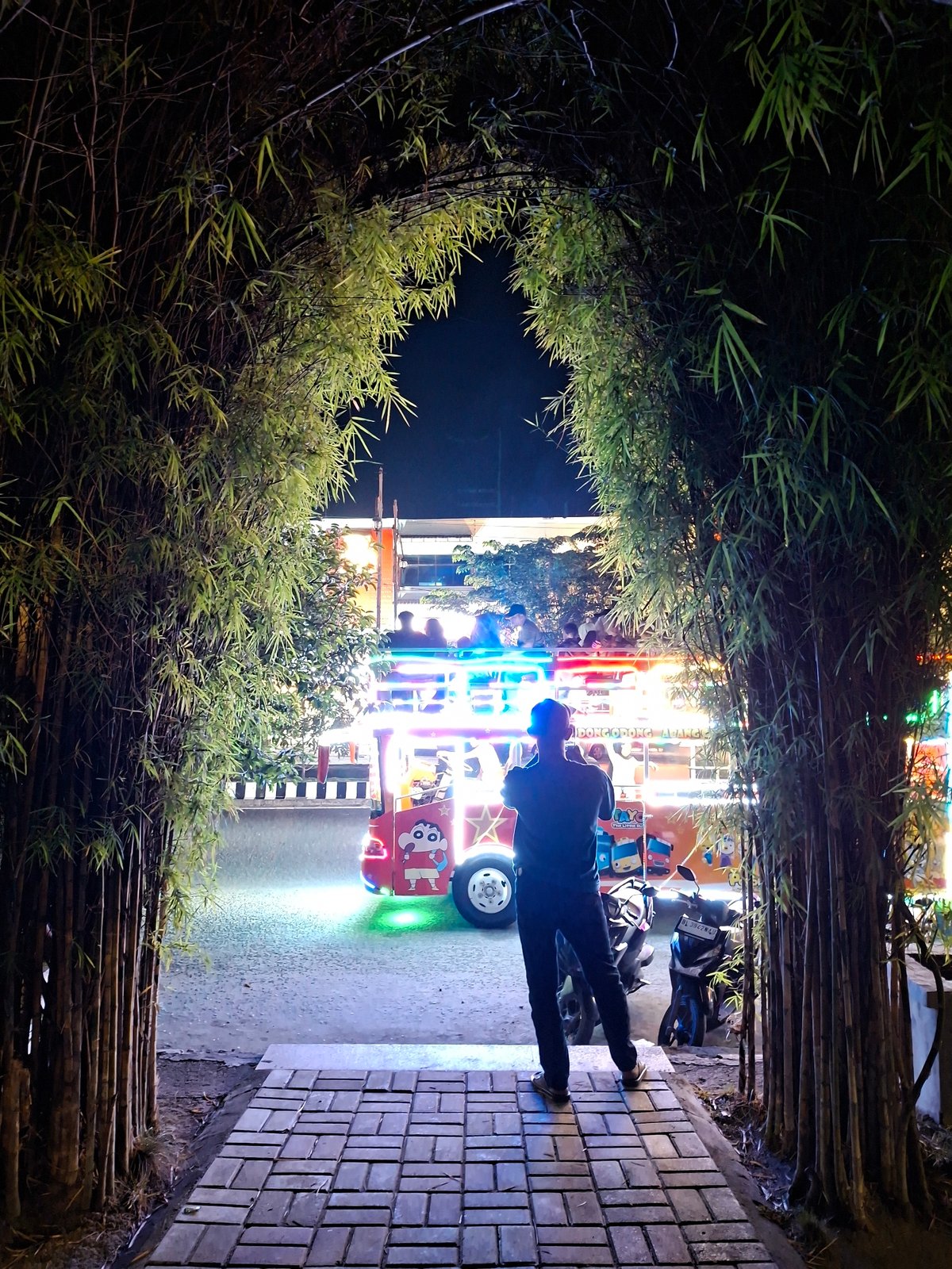 Person watches carnival ride from walkway in Lhokseumawe