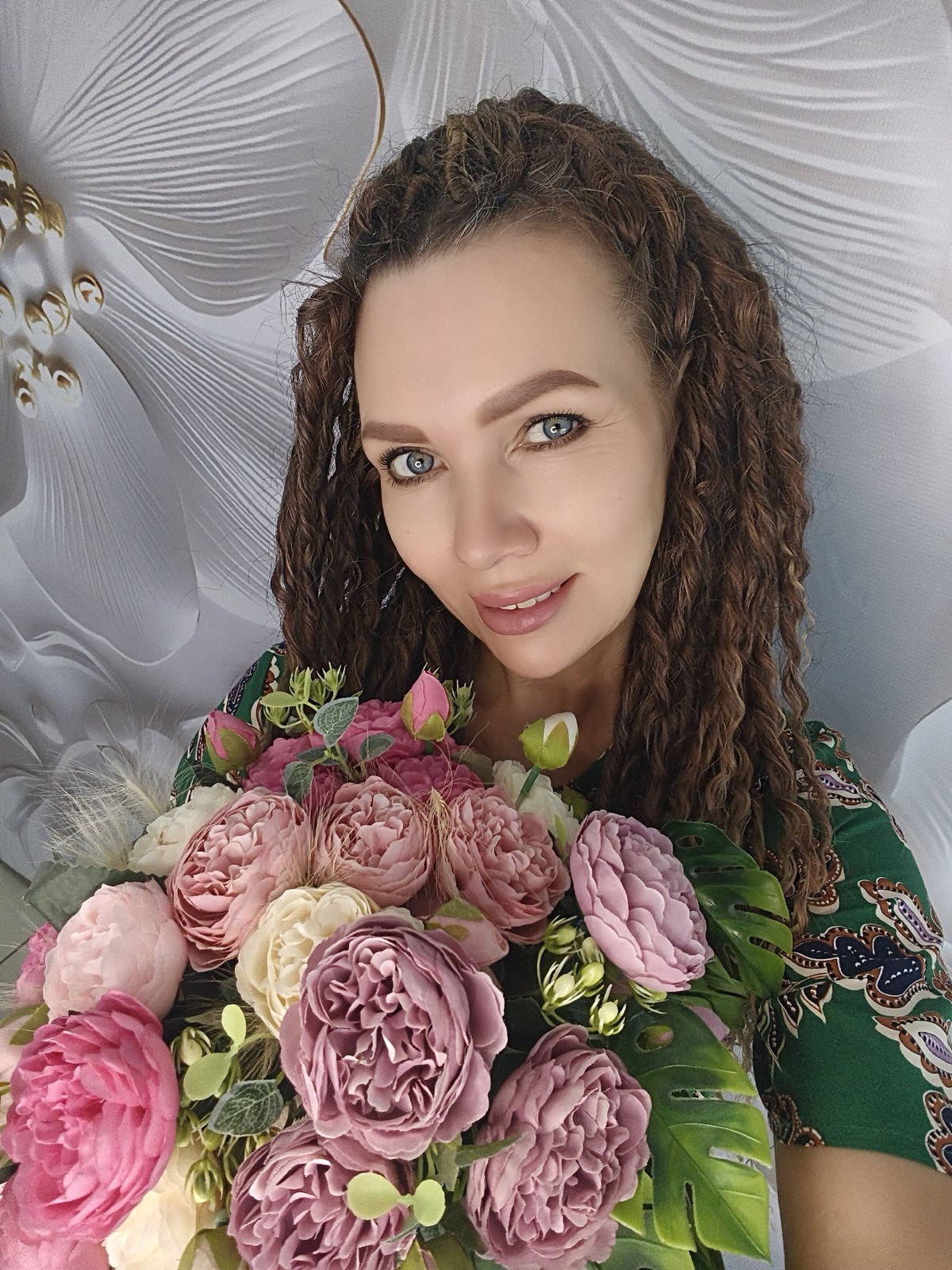 Woman poses with colorful flower bouquet in green dress