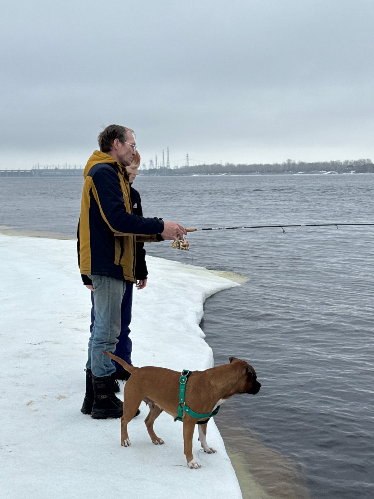 Family fishing trip with playful dog on frozen Russian reservoir