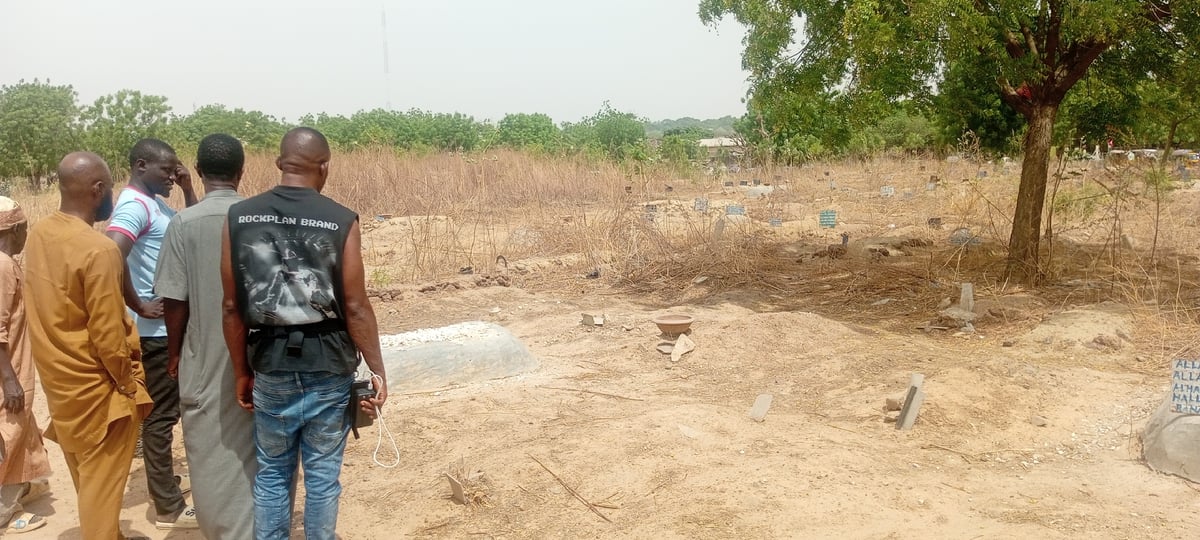 Men in mixed attire gather at city graveyard
