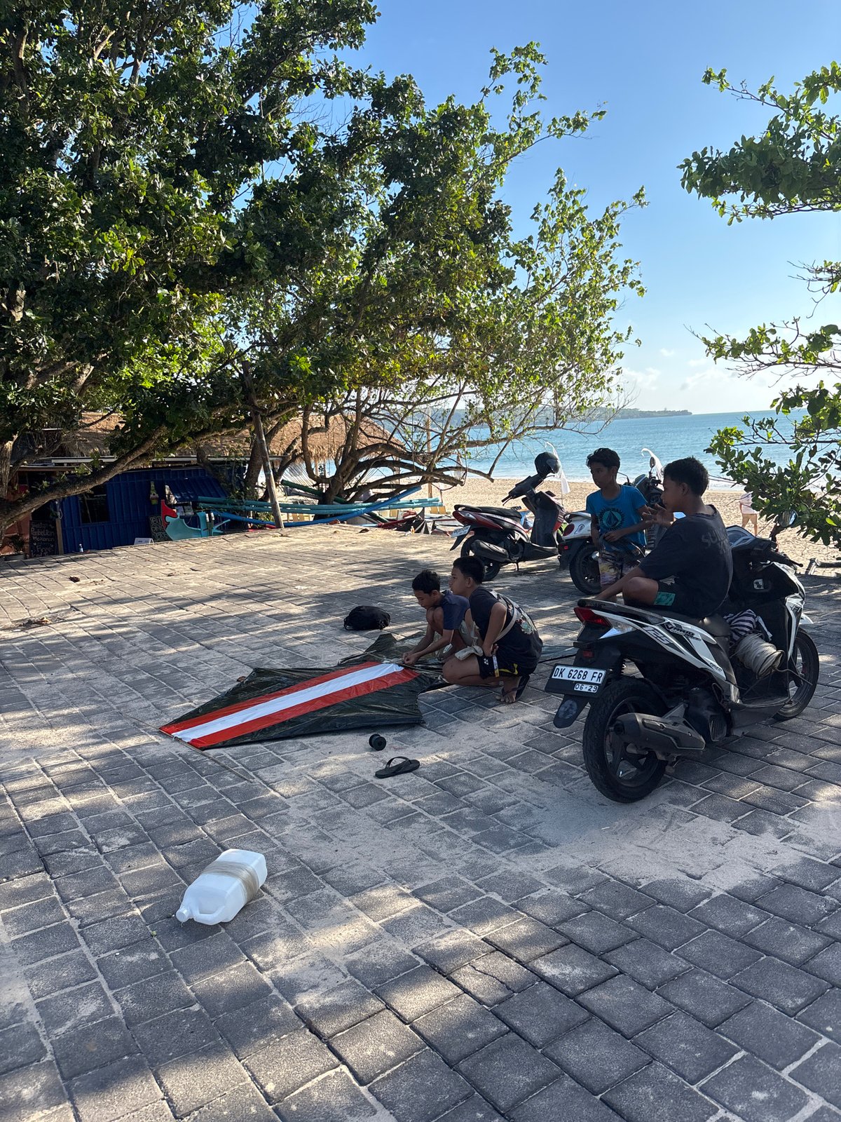 Young men gather on Kuta beach pathway during sunny morning