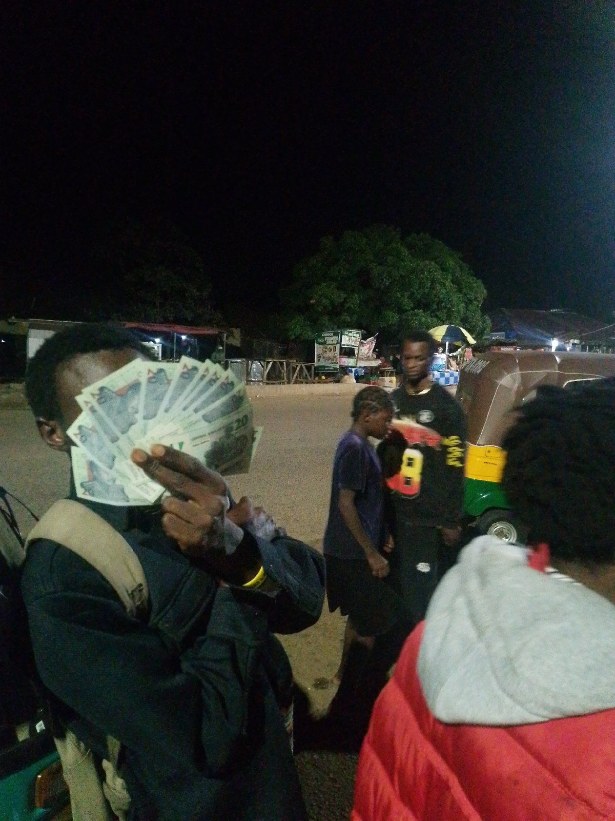 Nighttime street activity: food vendors, vehicles, and cash exchanges