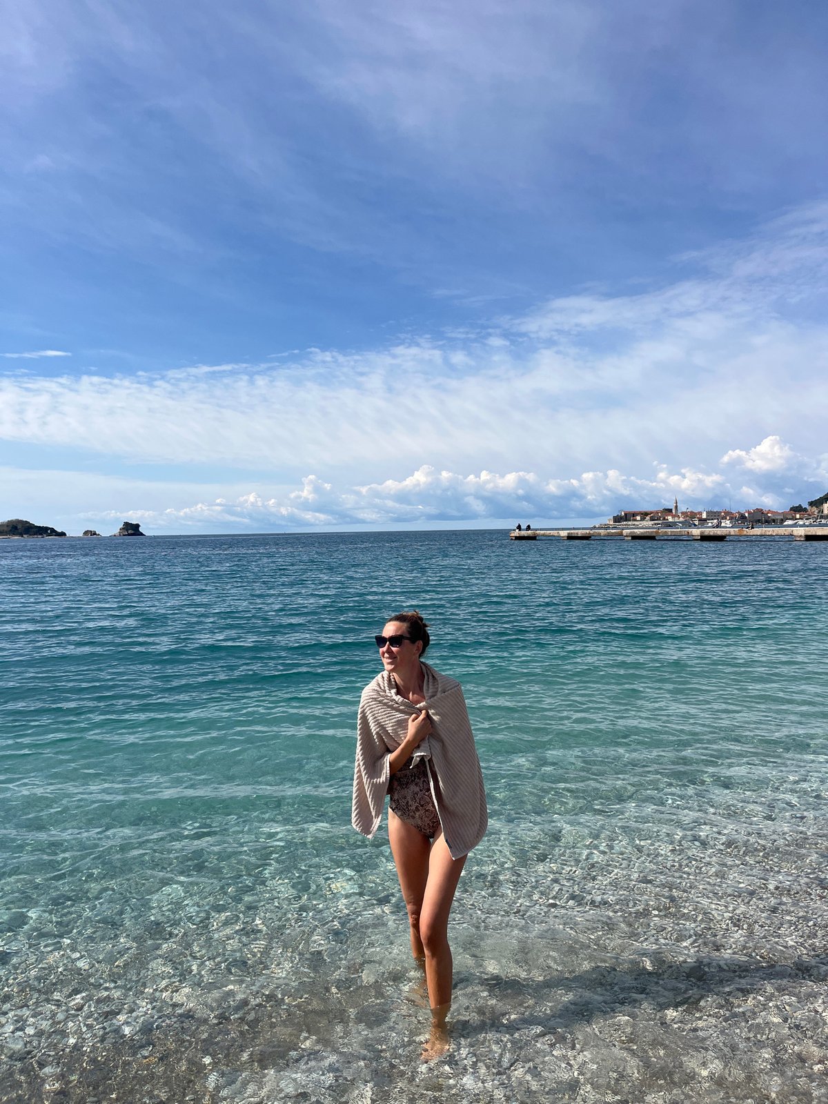 Woman stands in clear coastal waters in Budva