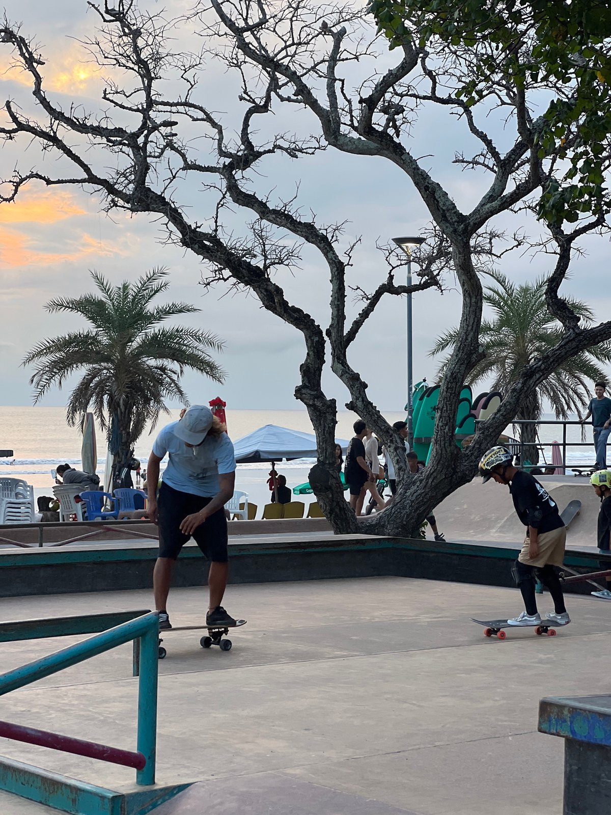 Skateboarders practice tricks at Kuta beachside park during sunset
