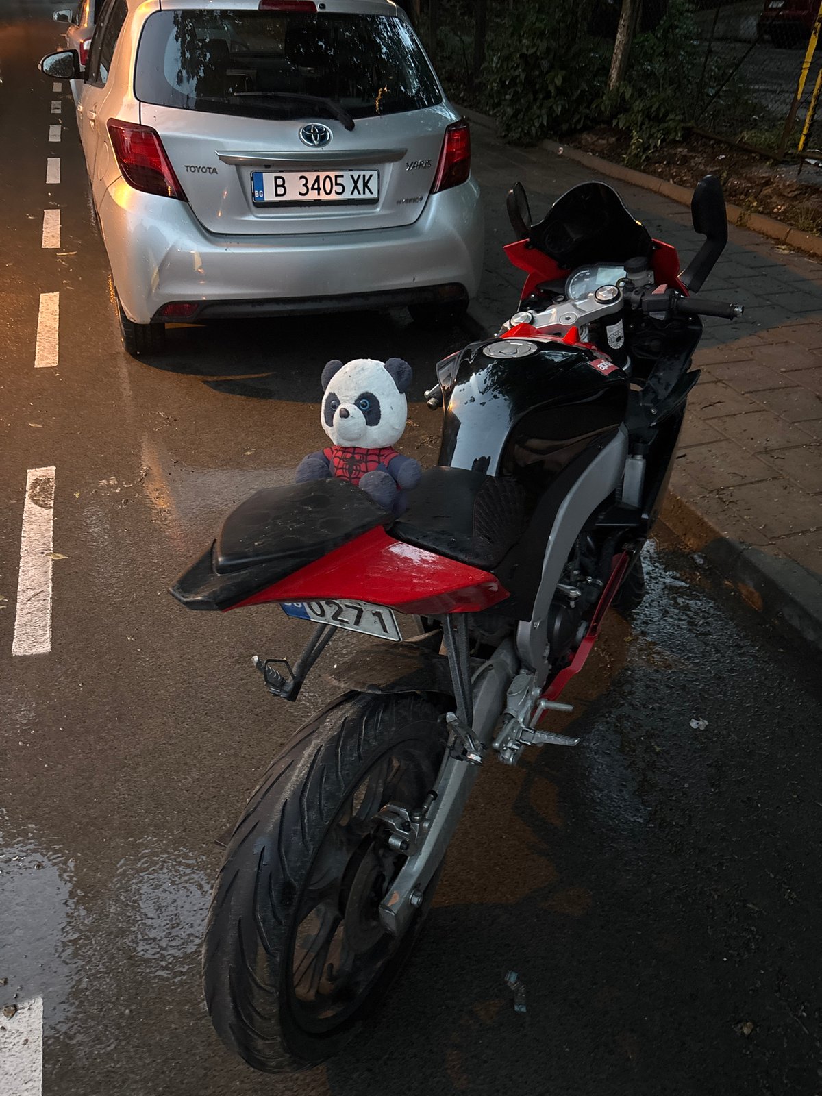 Motorcycle and car parked on wet street in Varna