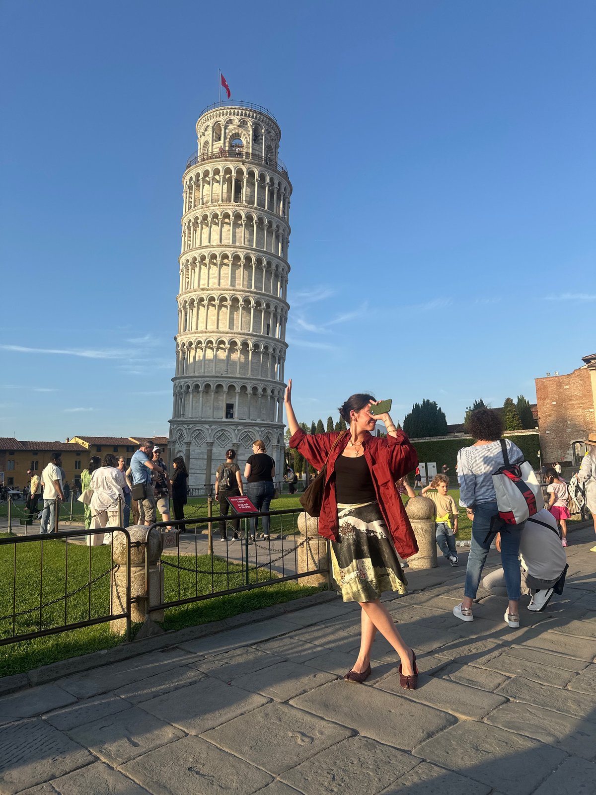 Tourists gather at Leaning Tower of Pisa during sunny afternoon