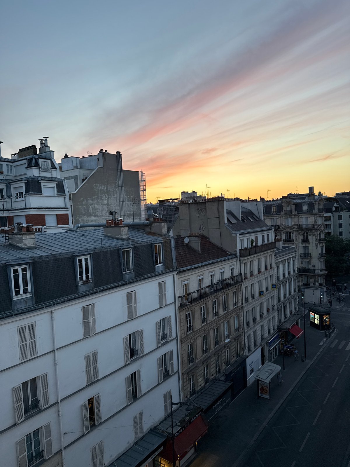 Rooftop-level Paris at golden hour, cafes and classic architecture