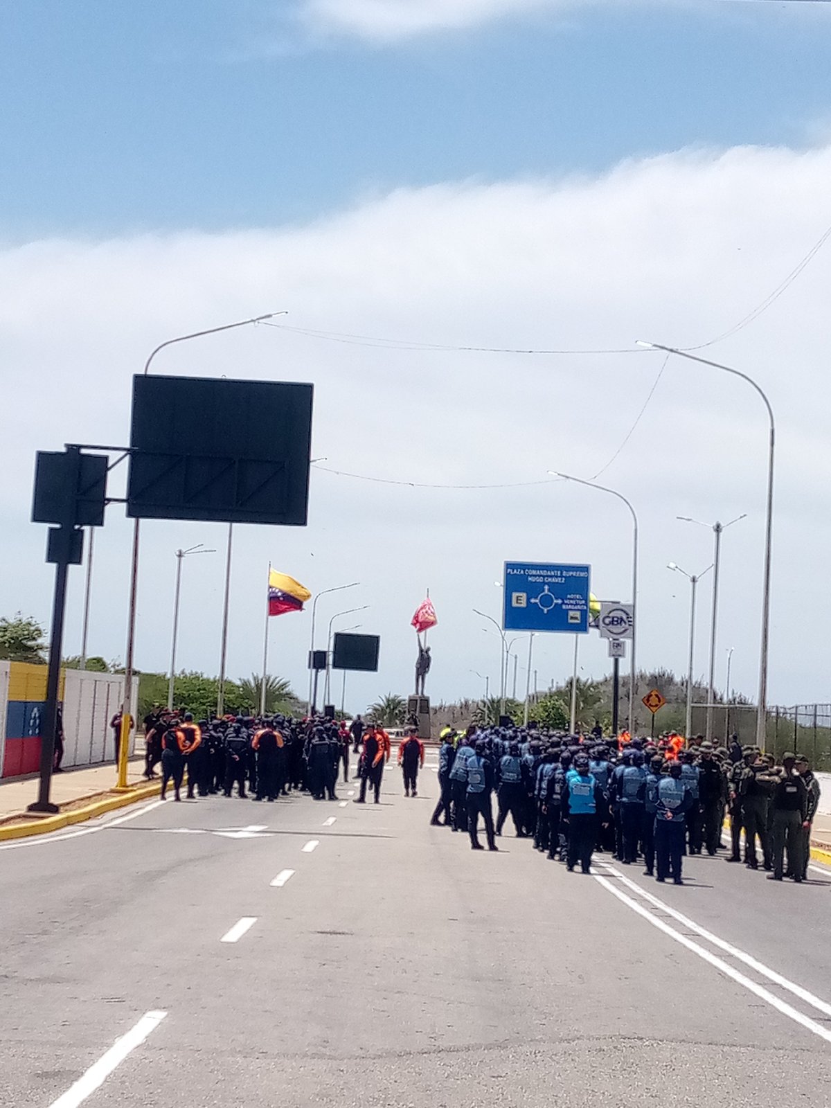 Uniformed personnel gather on busy Porlamar street during afternoon