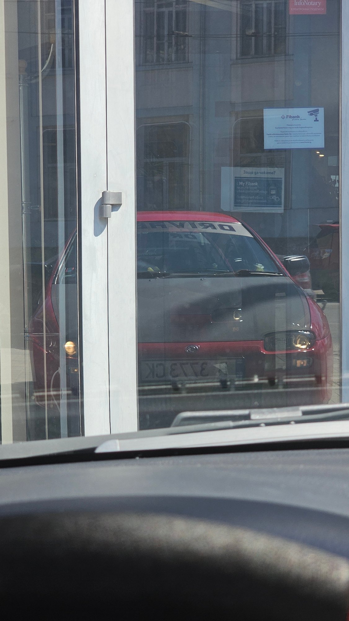 Van reflection captured in Fibank storefront window in Varna