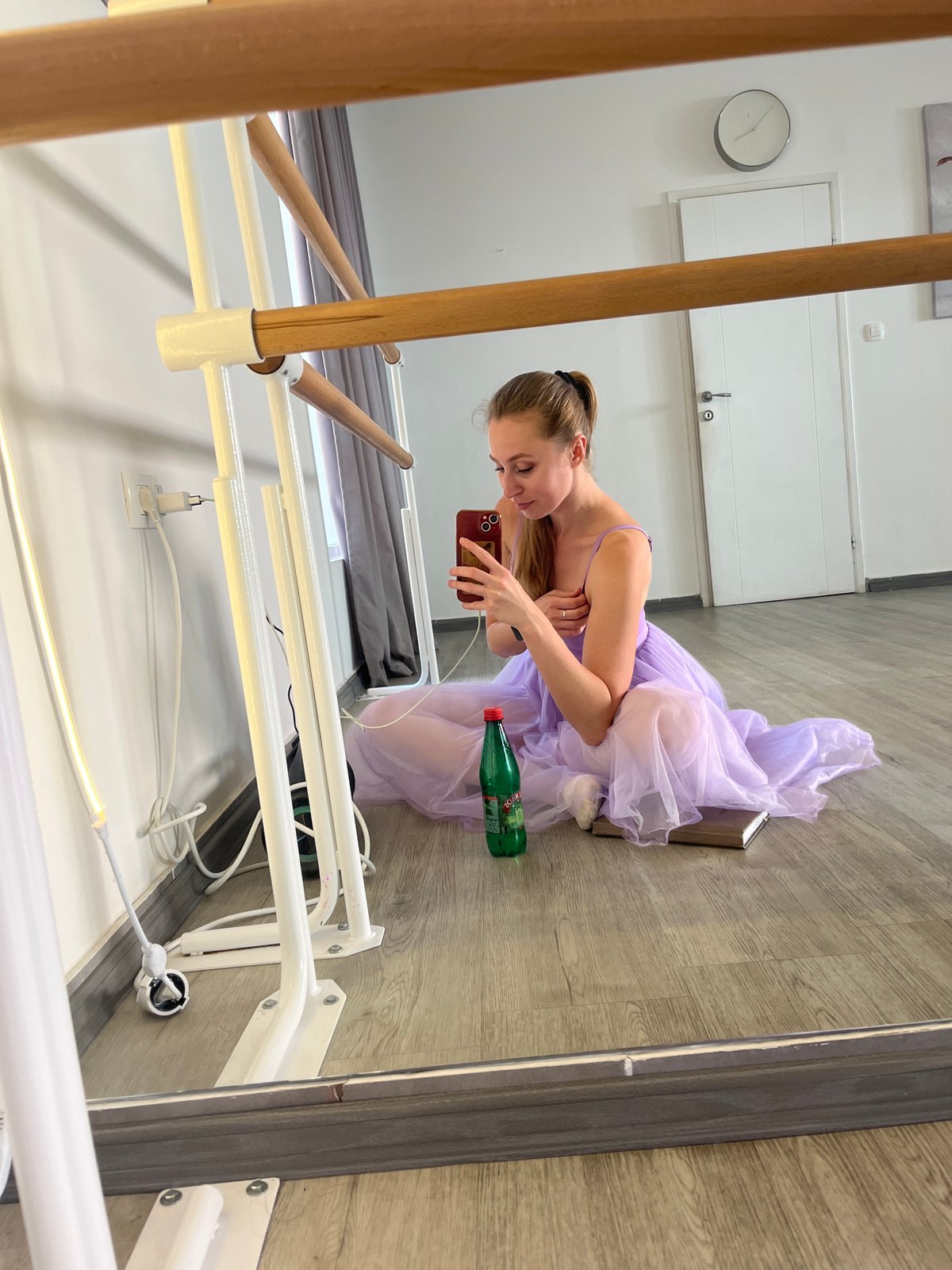 Ballerina with phone sits on book in Budva studio