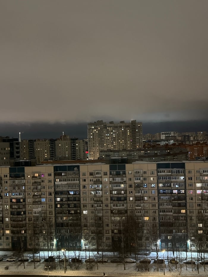 Saint Petersburg apartment towers glow against winter night fog