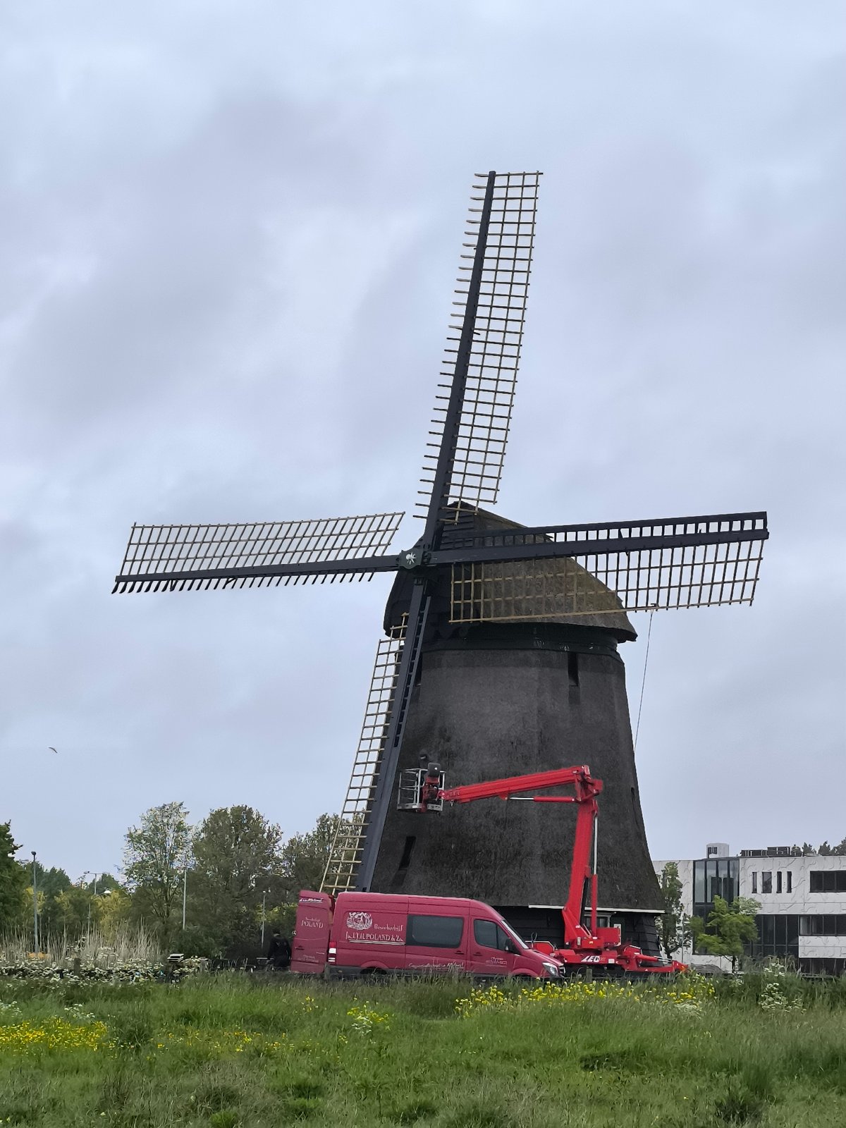 Industrial crane positioned near traditional windmill in Alkmaar