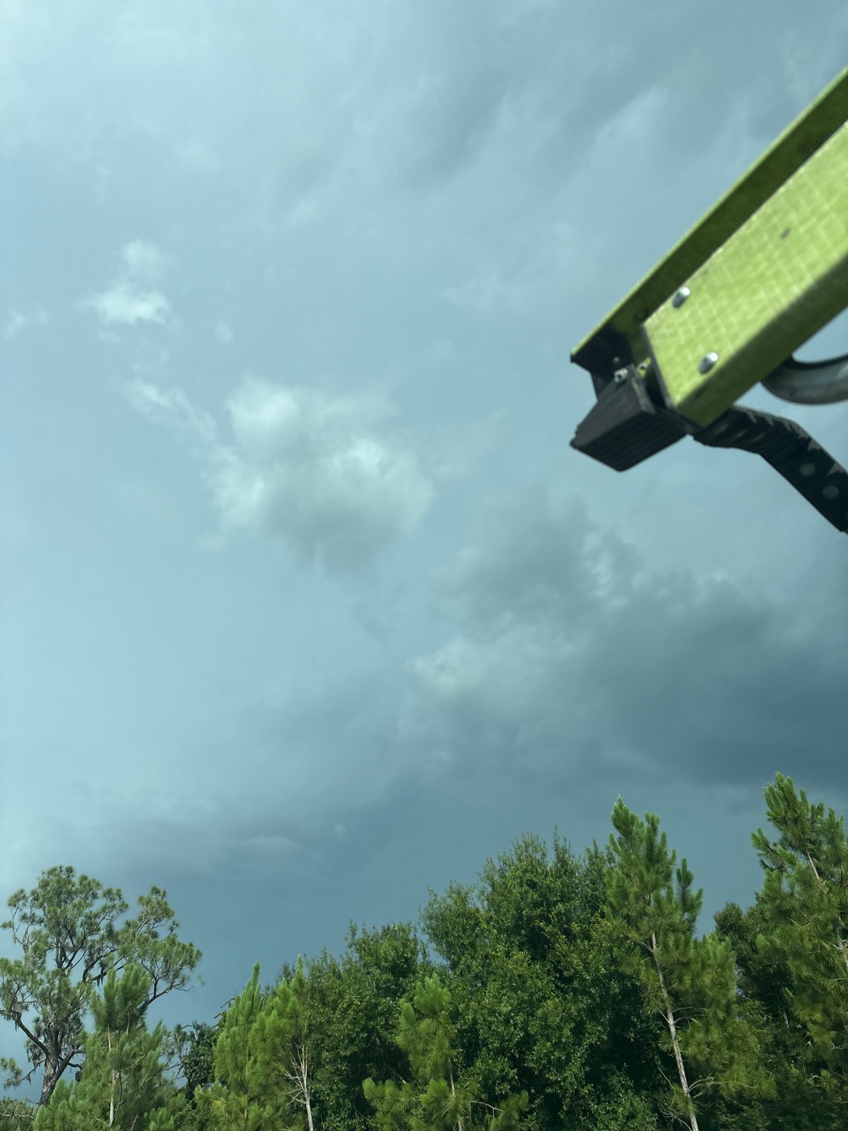Dark skies over Sarasota treeline, green rigging arm in frame