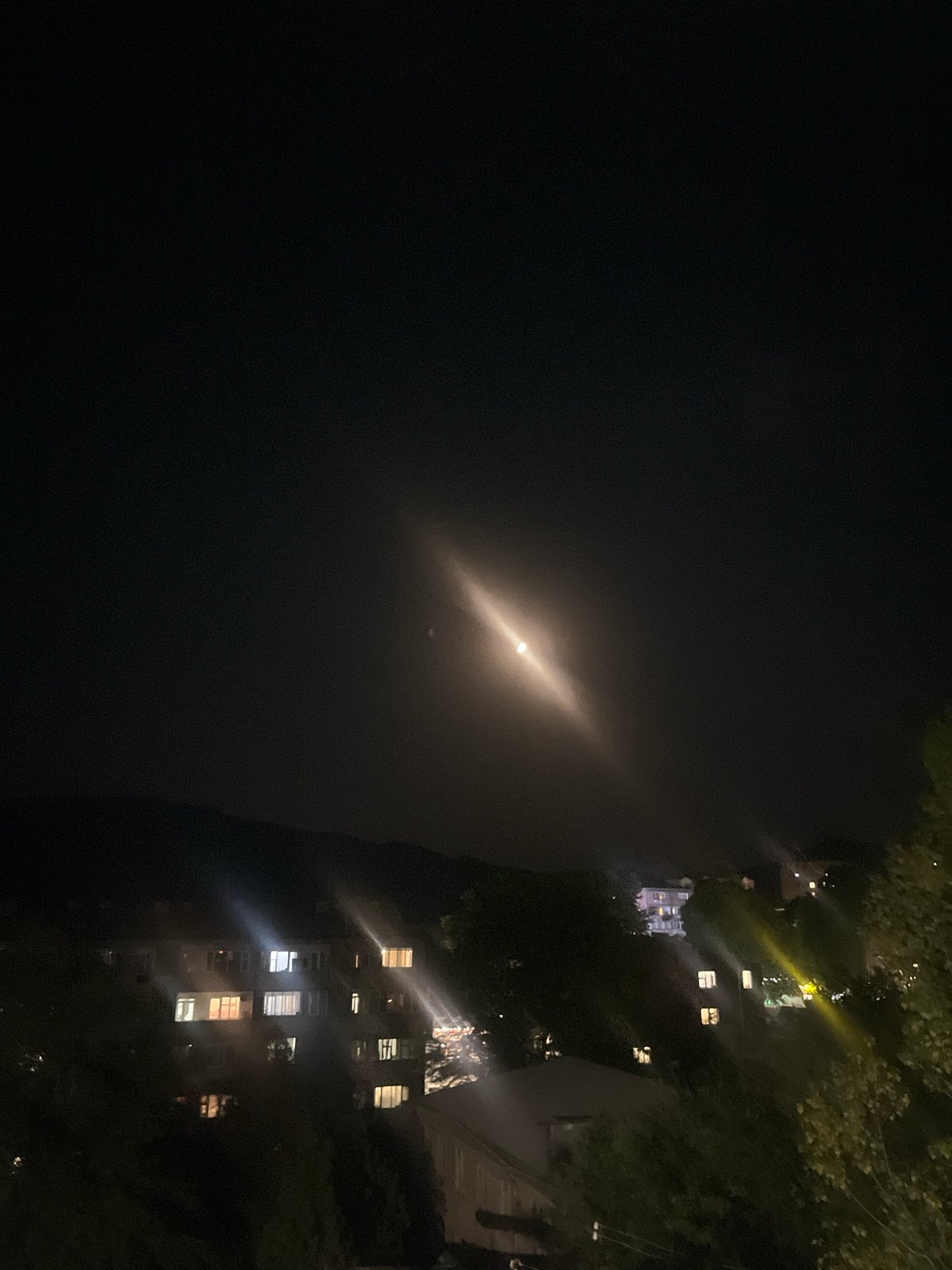Nighttime urban roaming with moon, buildings, and city lights