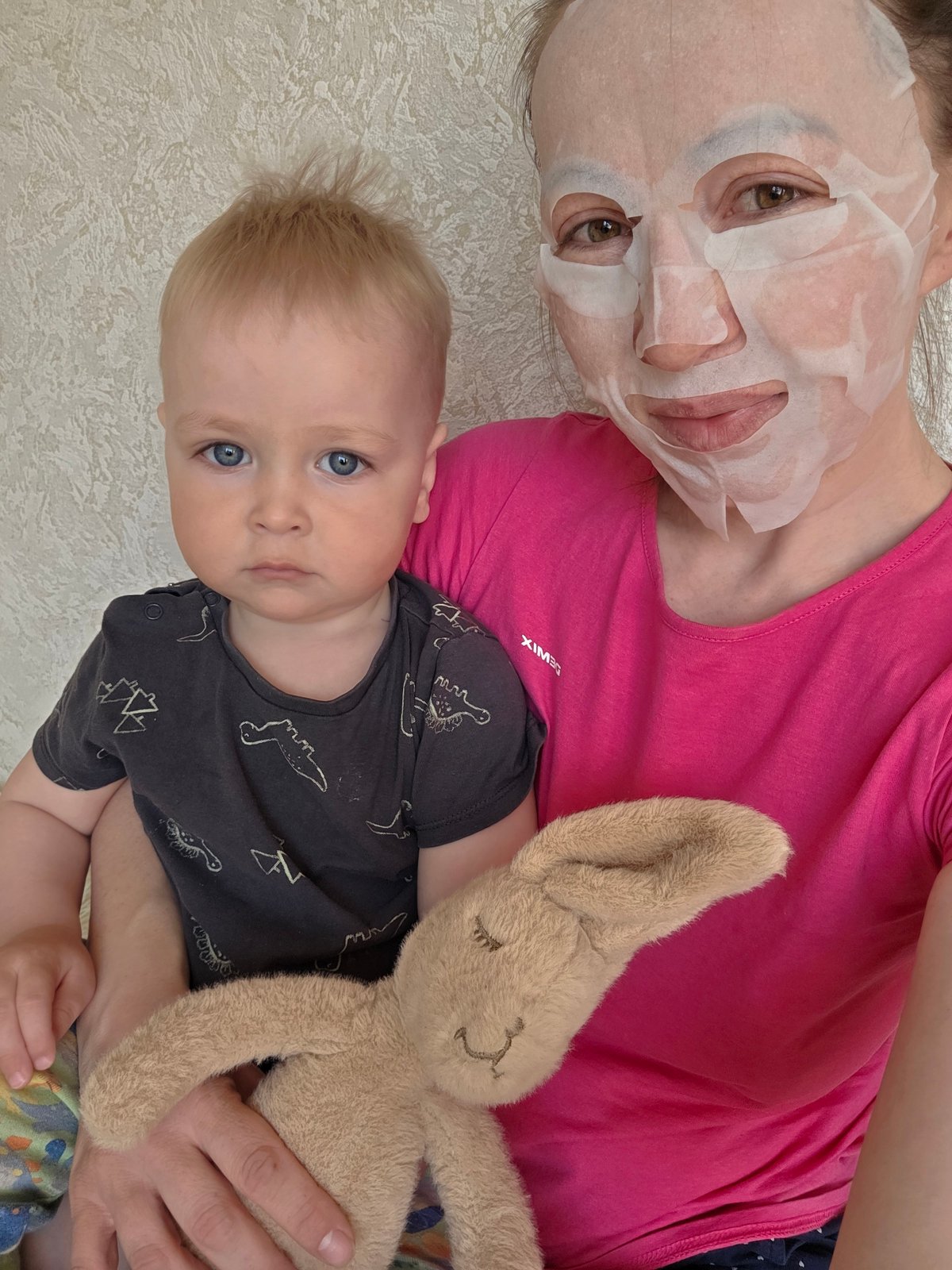 Woman in face mask lies with baby in Chaikovsky