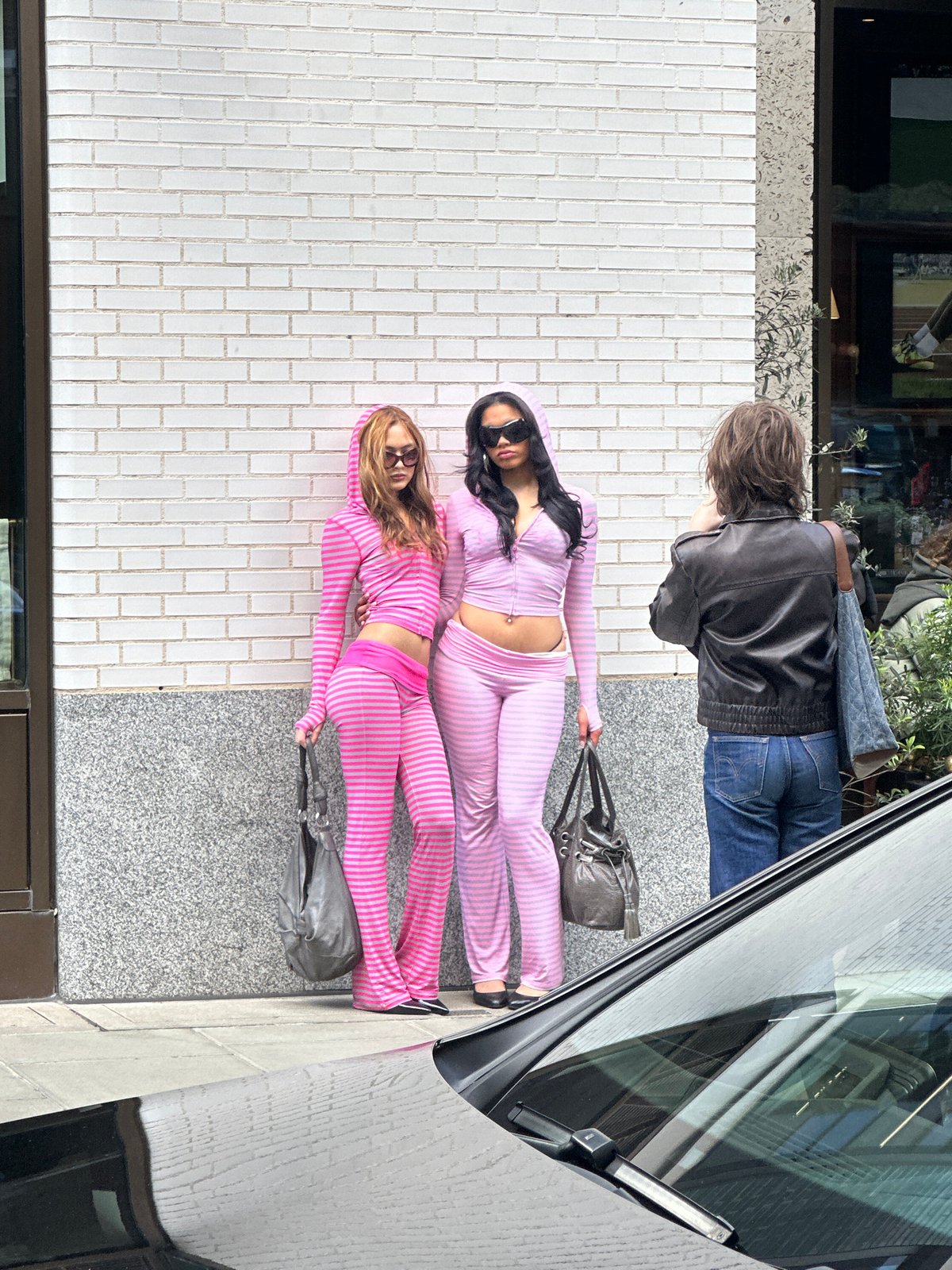 Two women in matching tracksuits lie on London pavement