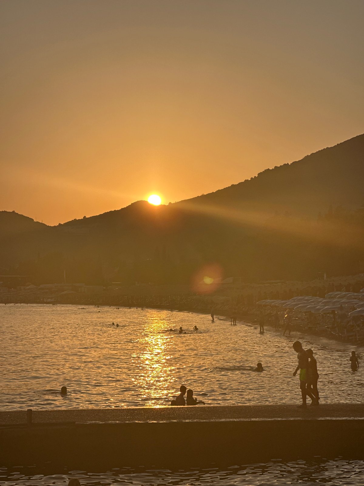 Sunset hour on the Budva waterfront: boats, parasails, and a sleeping cat