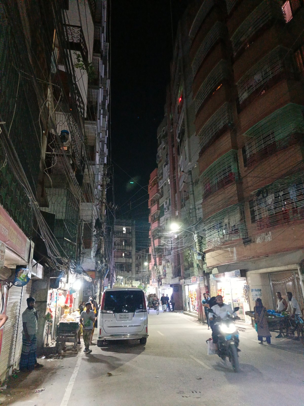 Silver minivan blocks street at night under power lines