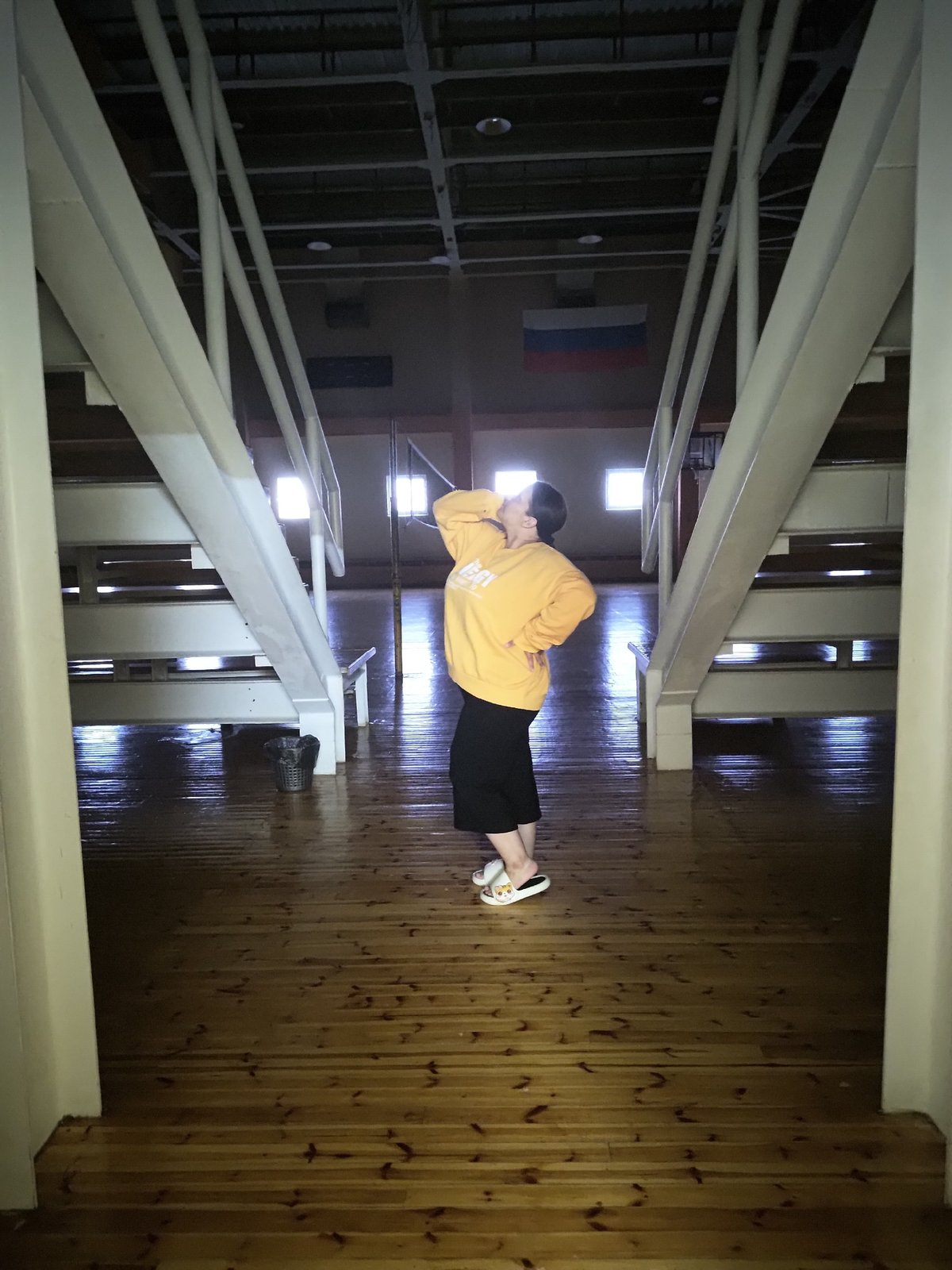 Person in orange sweatshirt lies on gymnasium floor