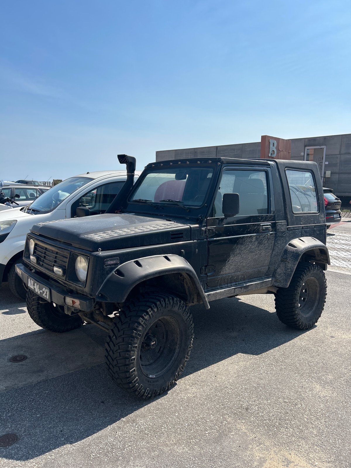 Lifted Suzuki Samurai and yellow Mercedes van parked on a sunny day