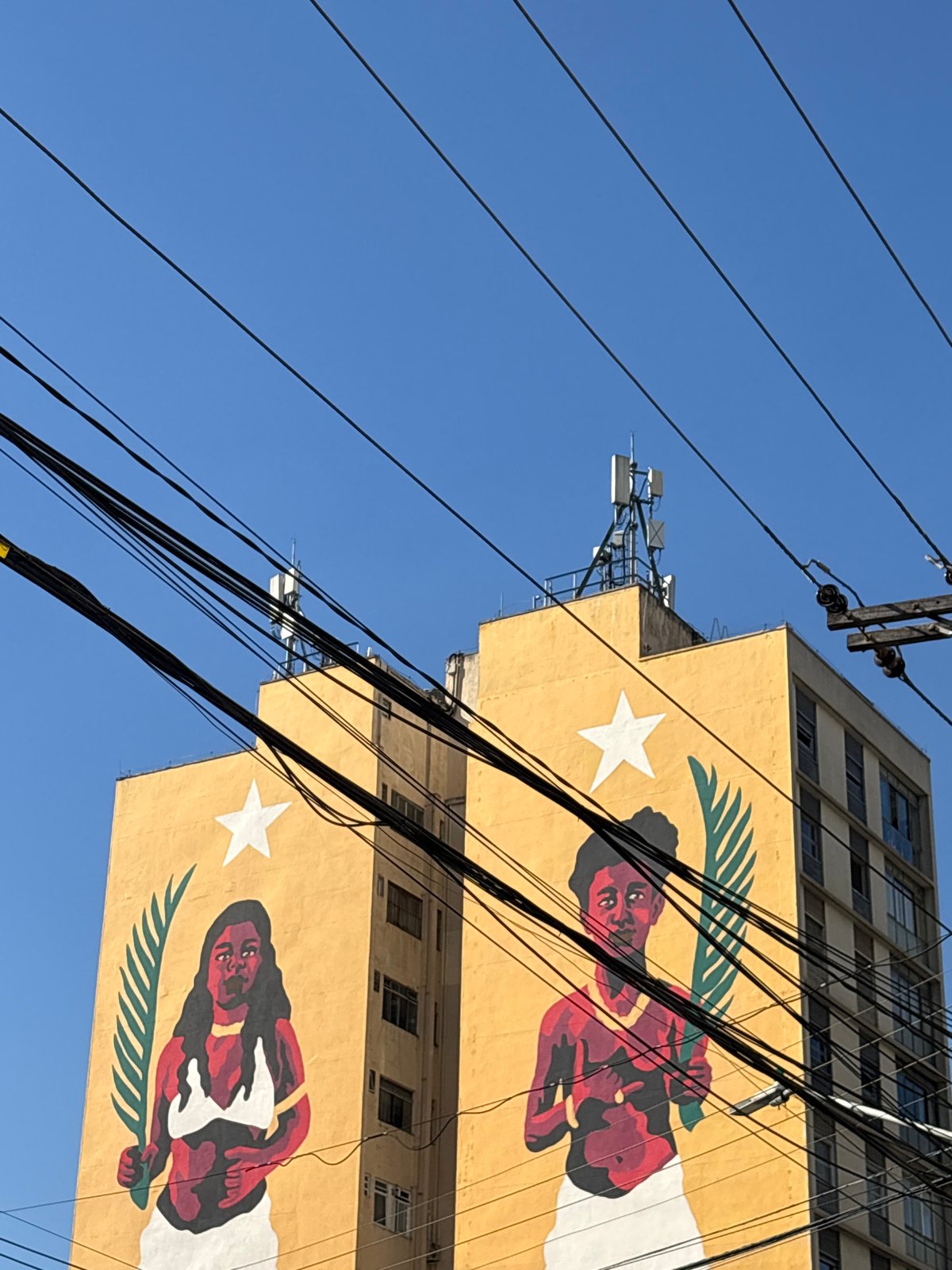 Bold street mural on a São Paulo building, shot from below