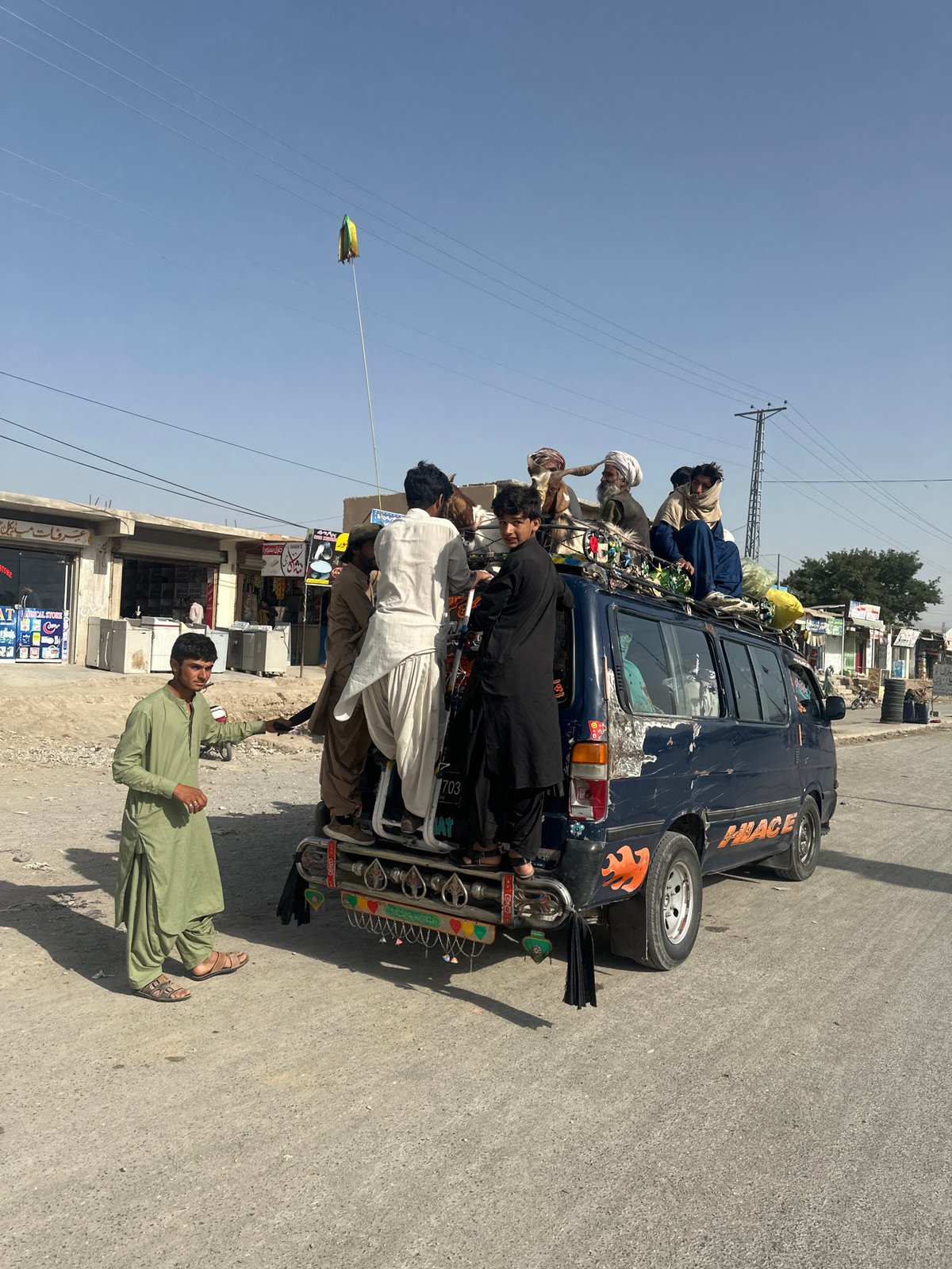 Overloaded decorated van carries passengers on roof in Quetta