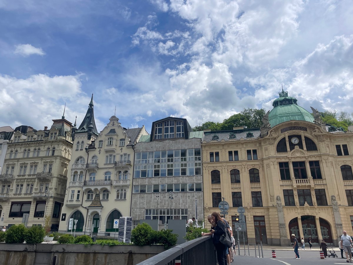 Tourists document Karlovy Vary's historic architecture during overcast morning