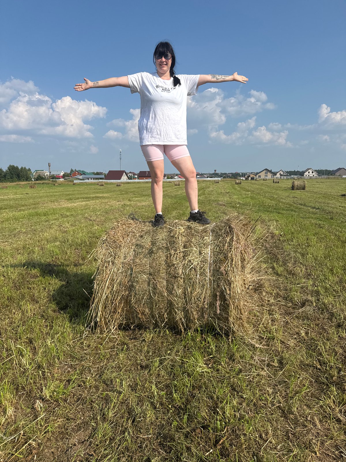 Balancing on a hay bale in a Russian summer field
