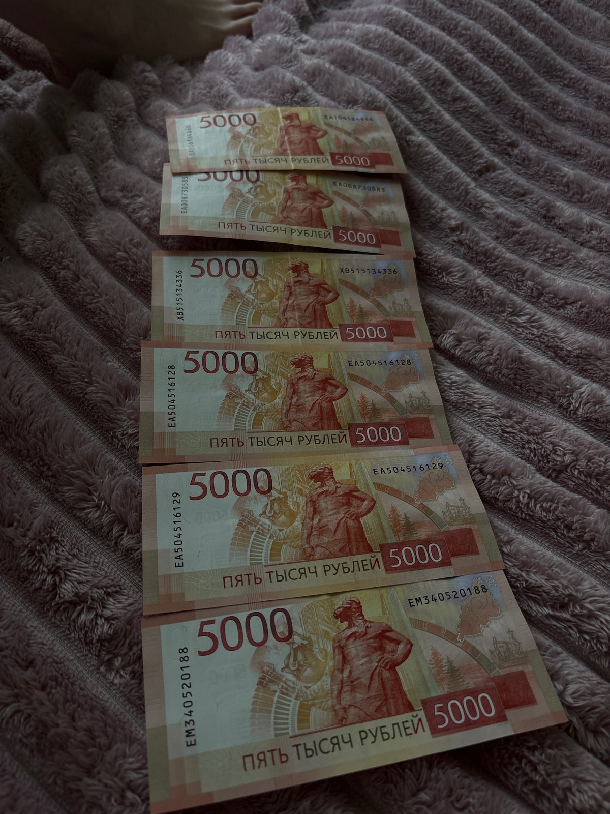 Person photographed with Russian currency and jewelry on blanket