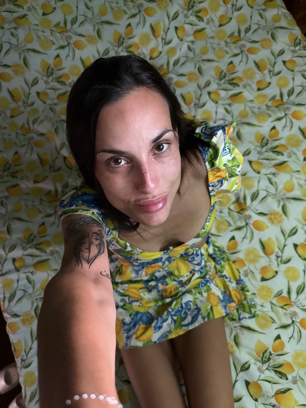 Woman photographed in lemon-print dress on matching sheets, Pleven