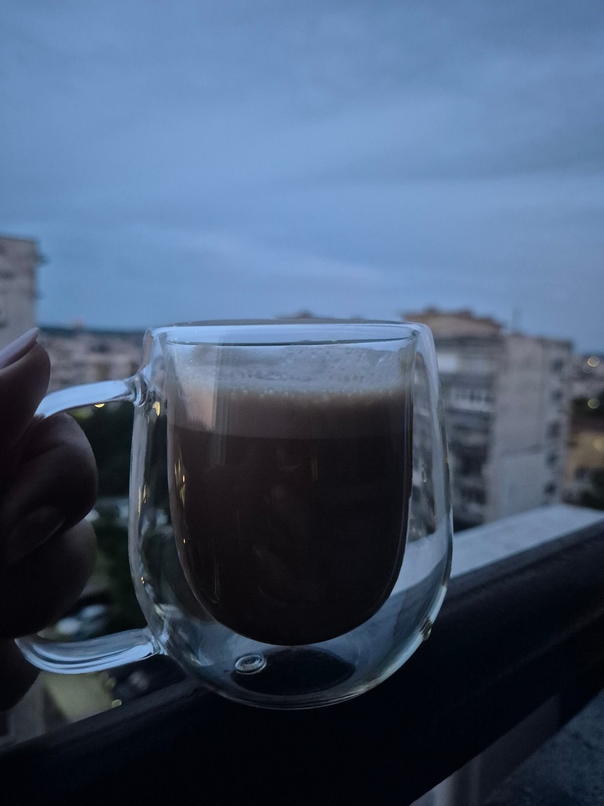 Coffee in hand, dusk settling over the city rooftops