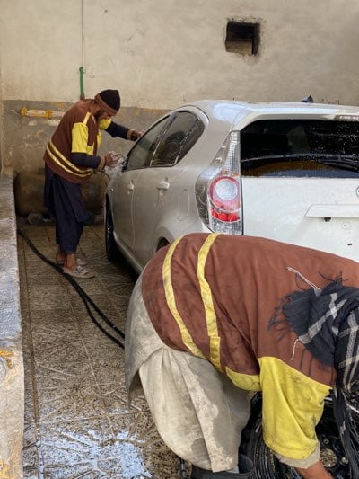 Car wash attendants clean white hatchback in Kandahar