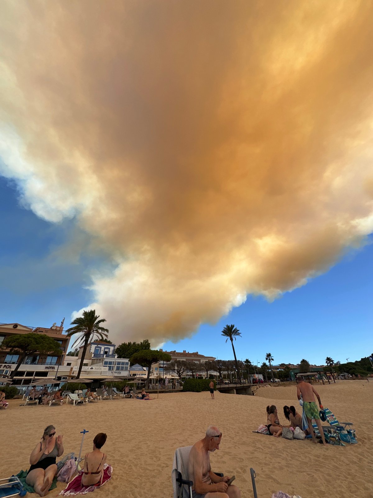 Wildfire smoke blankets Sant Feliu de Guíxols beach on a summer morning