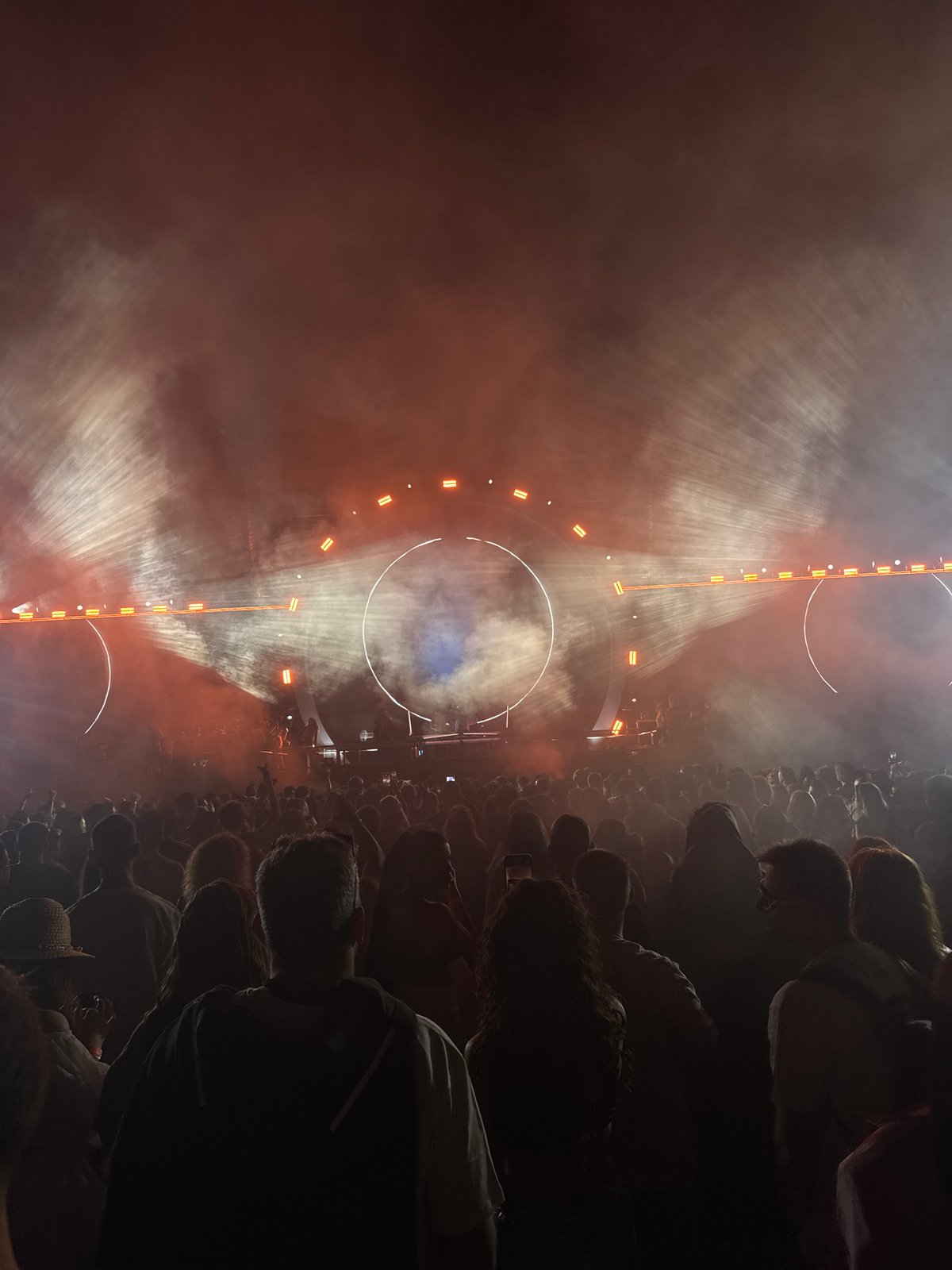 Big outdoor concert, circular solar stage backdrop, packed crowd