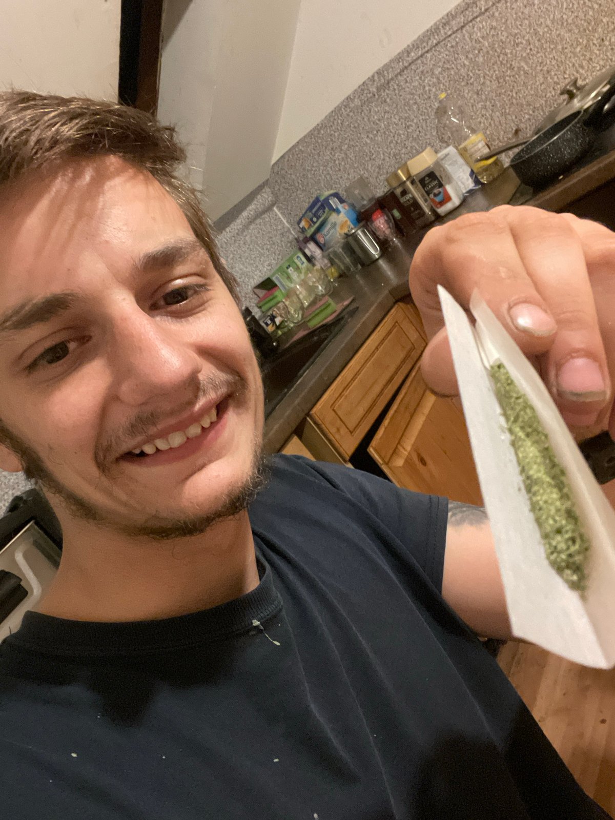 Man photographed with hand-rolled cigarette in kitchen setting