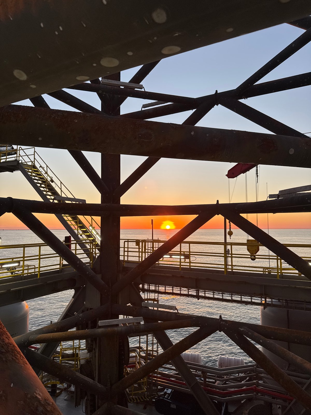 Offshore drilling operations documented during sunset in Italian waters