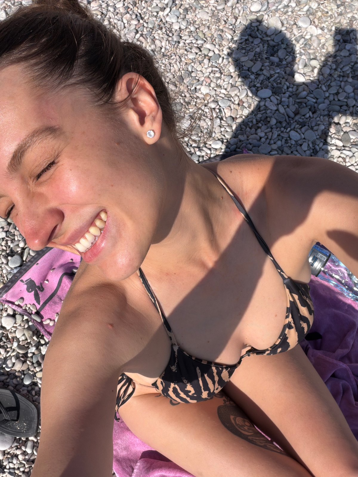 Woman sunbathes on pebble beach in Drobnići, Montenegro
